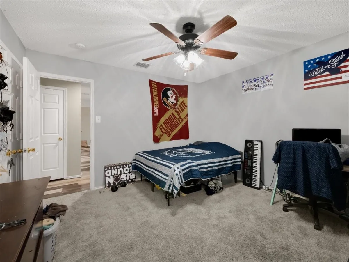 Carpeted bedroom with ceiling fan and a textured ceiling