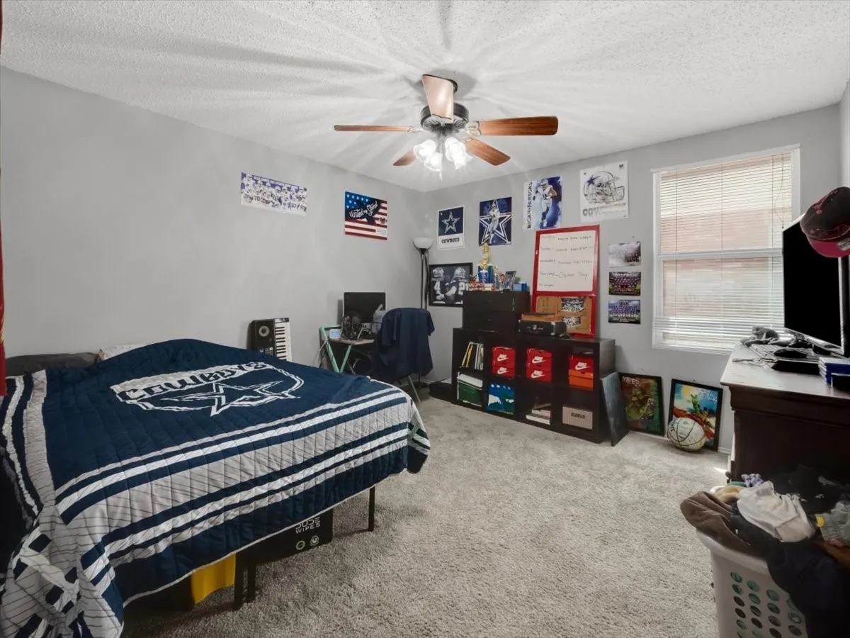 Bedroom featuring a textured ceiling, ceiling fan, and light carpet