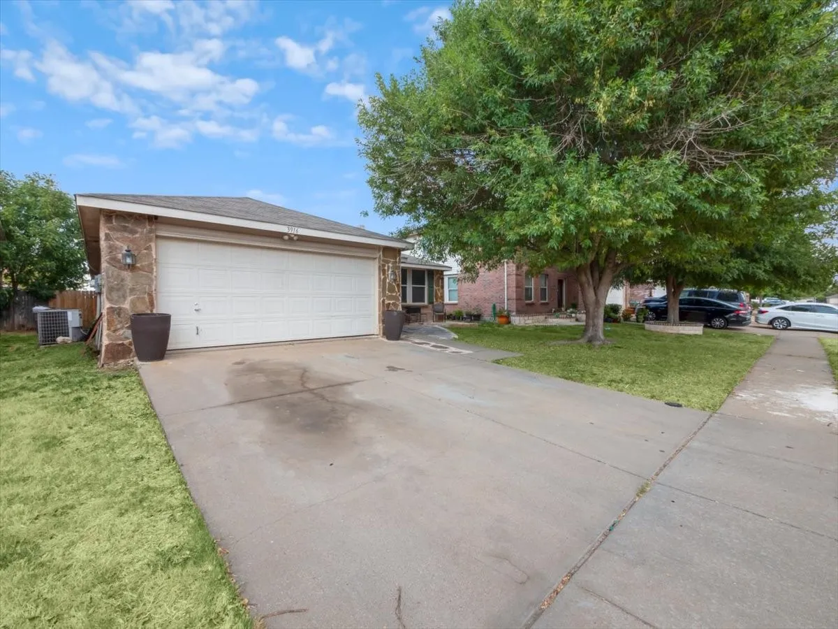 View of front of house featuring a front lawn, a garage, and central air condition unit