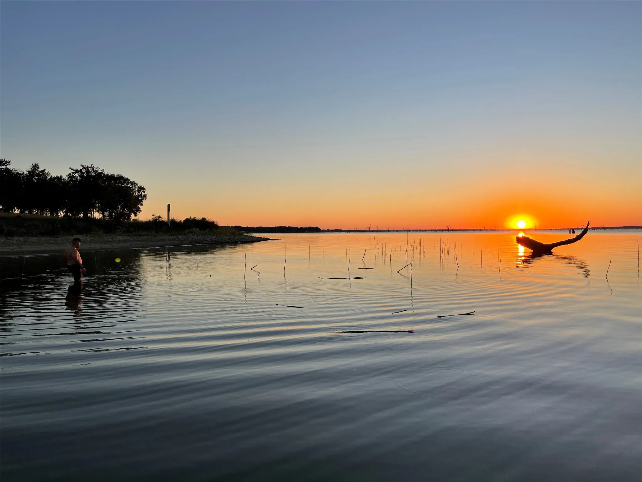 Spectacular sunset reflects across the calm lake waters.