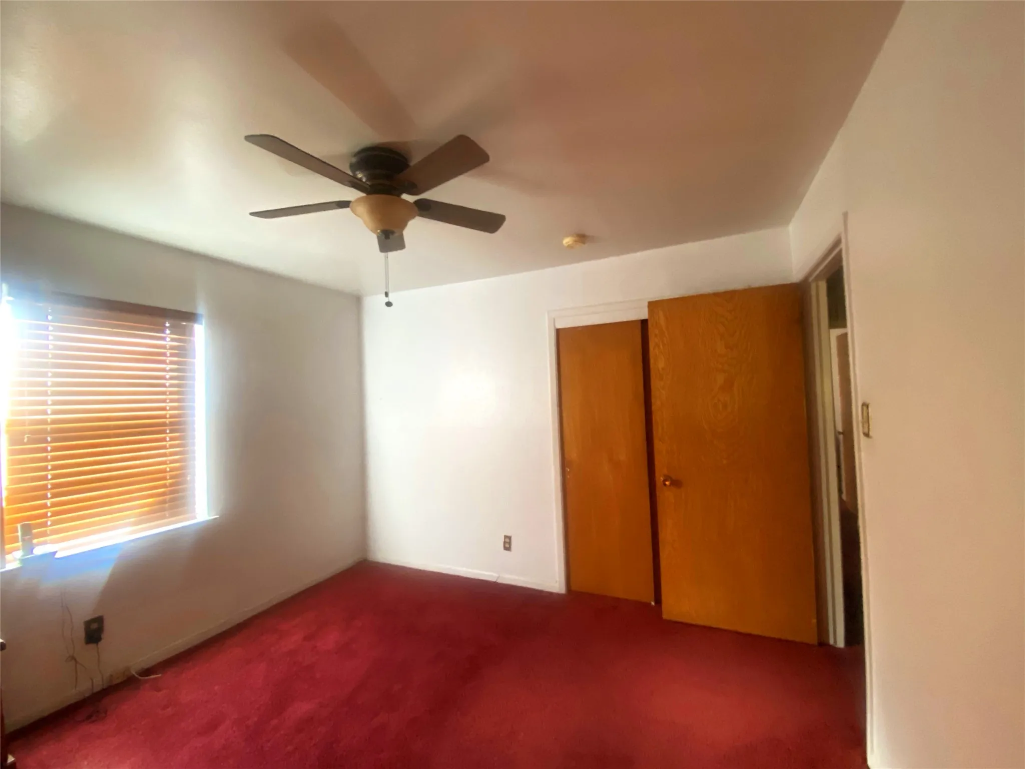 Unfurnished bedroom with ceiling fan, a closet, and dark carpet
