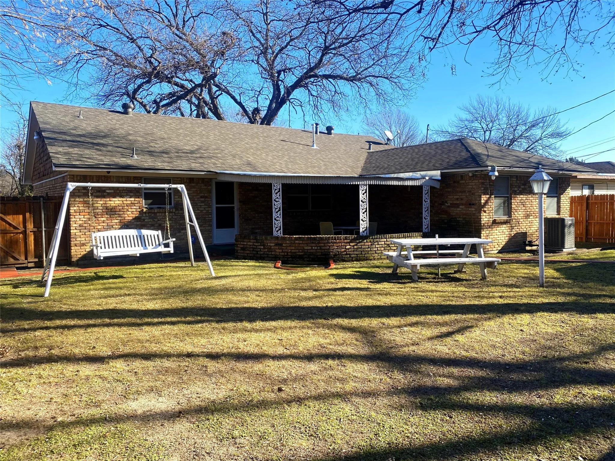 Rear view of house featuring a lawn and central AC