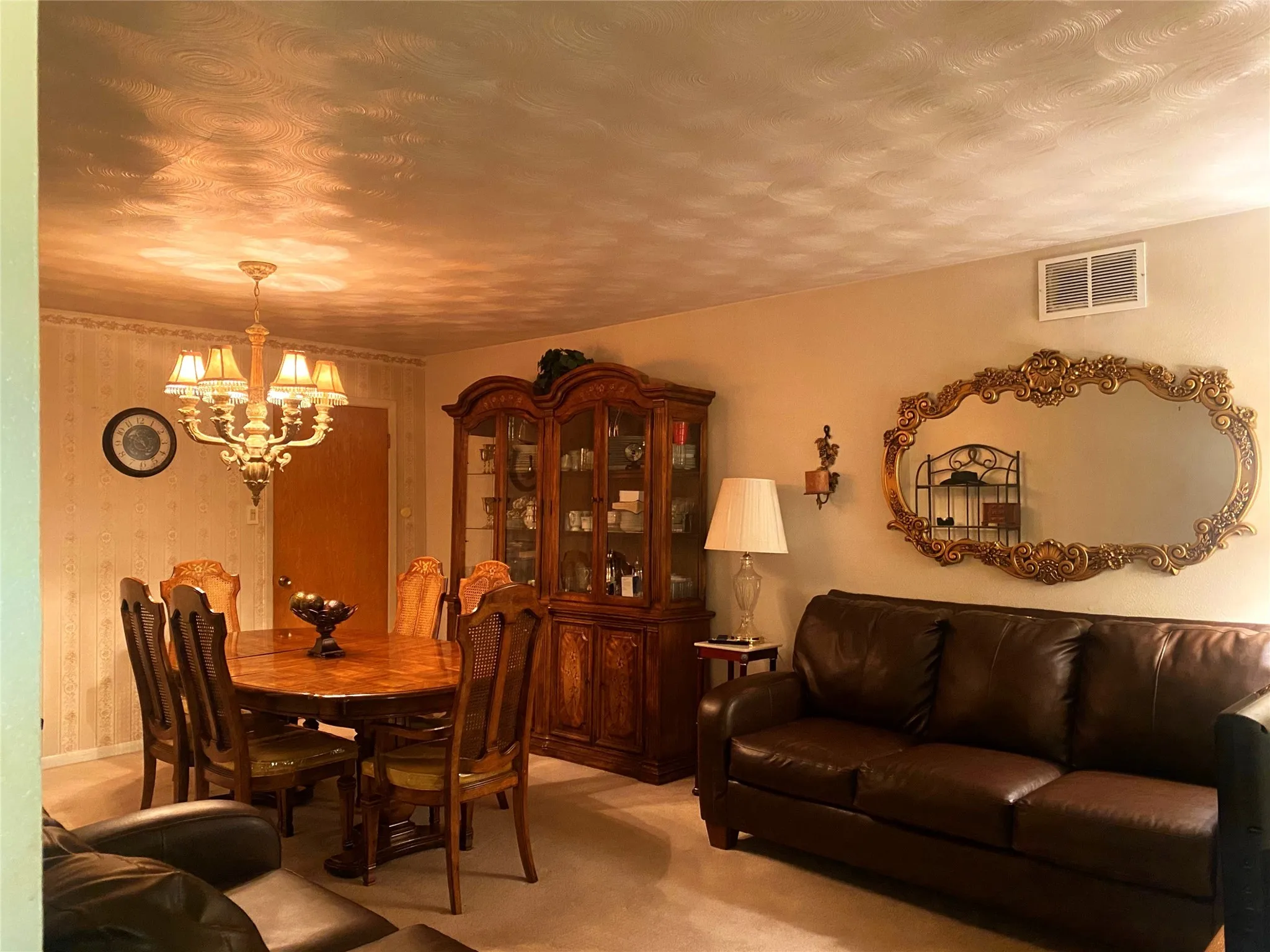Dining room with light carpet, a chandelier, and a textured ceiling