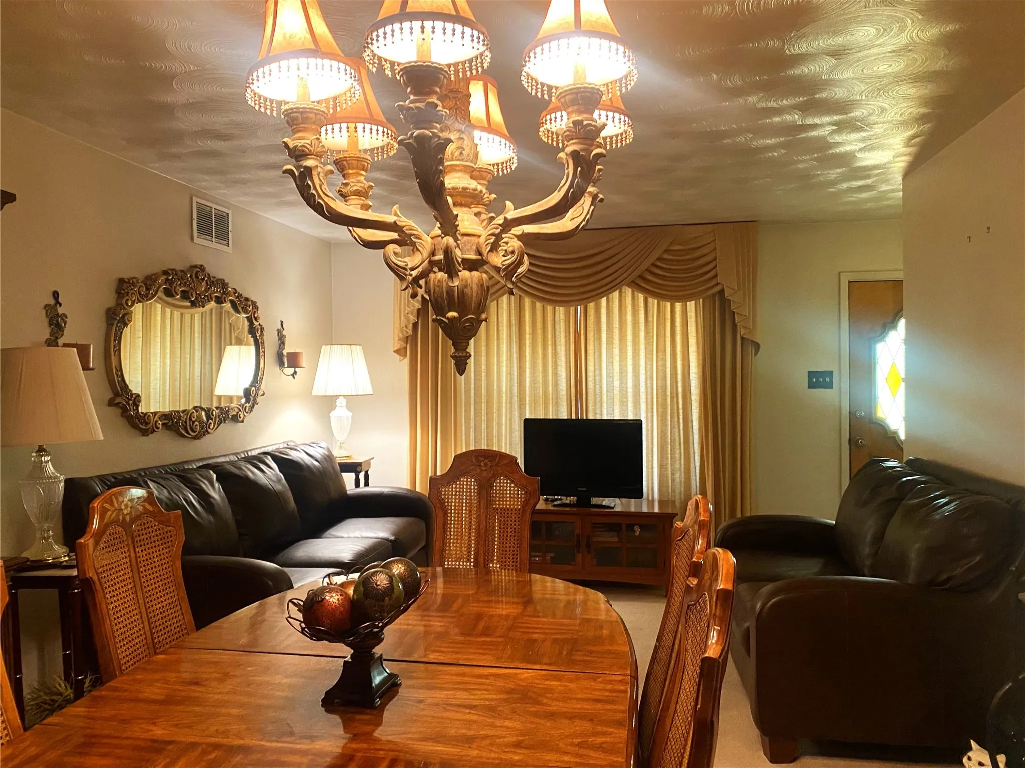 Carpeted living room with a textured ceiling and a notable chandelier