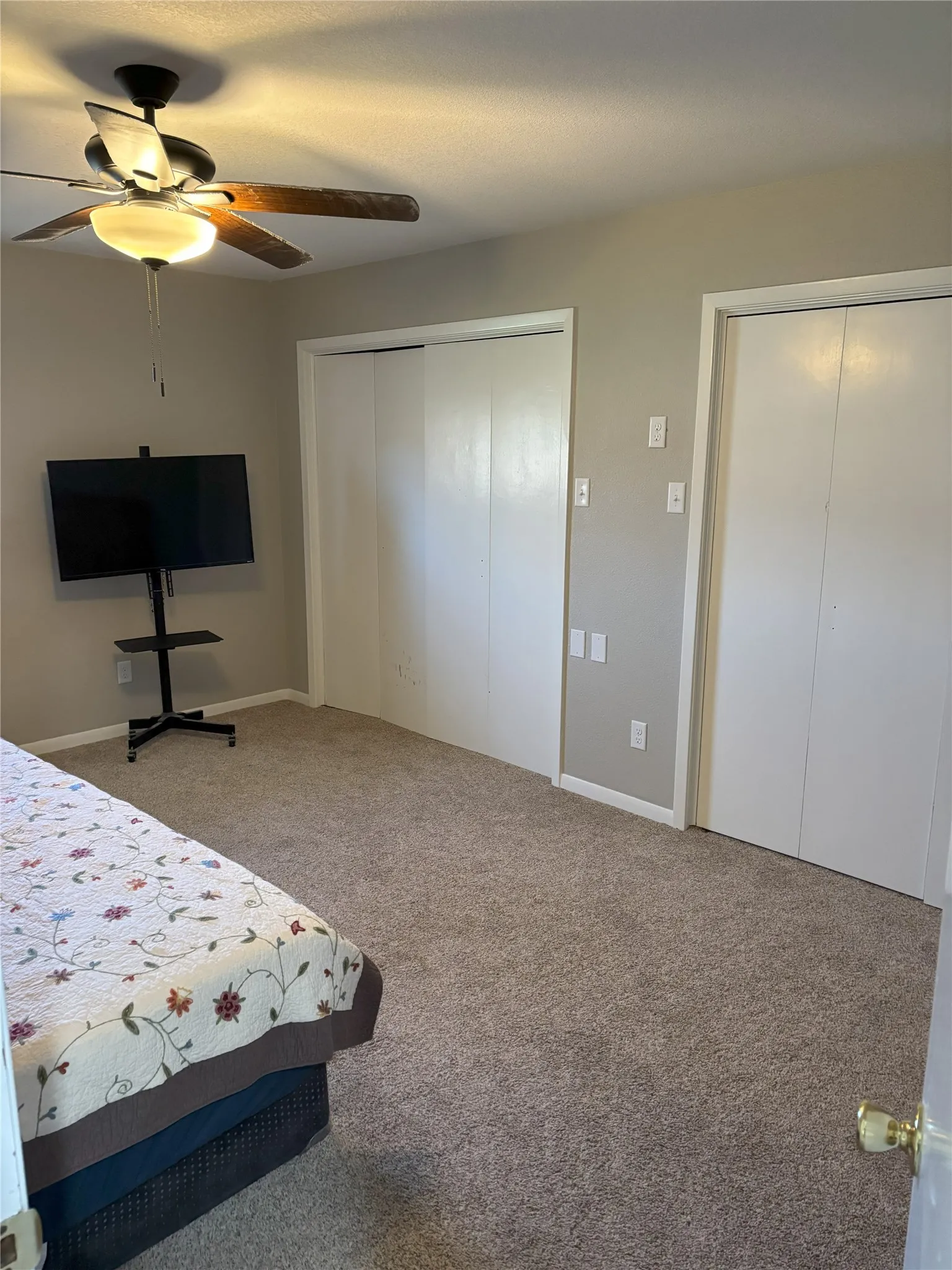 Bedroom featuring carpet floors, two closets, and ceiling fan