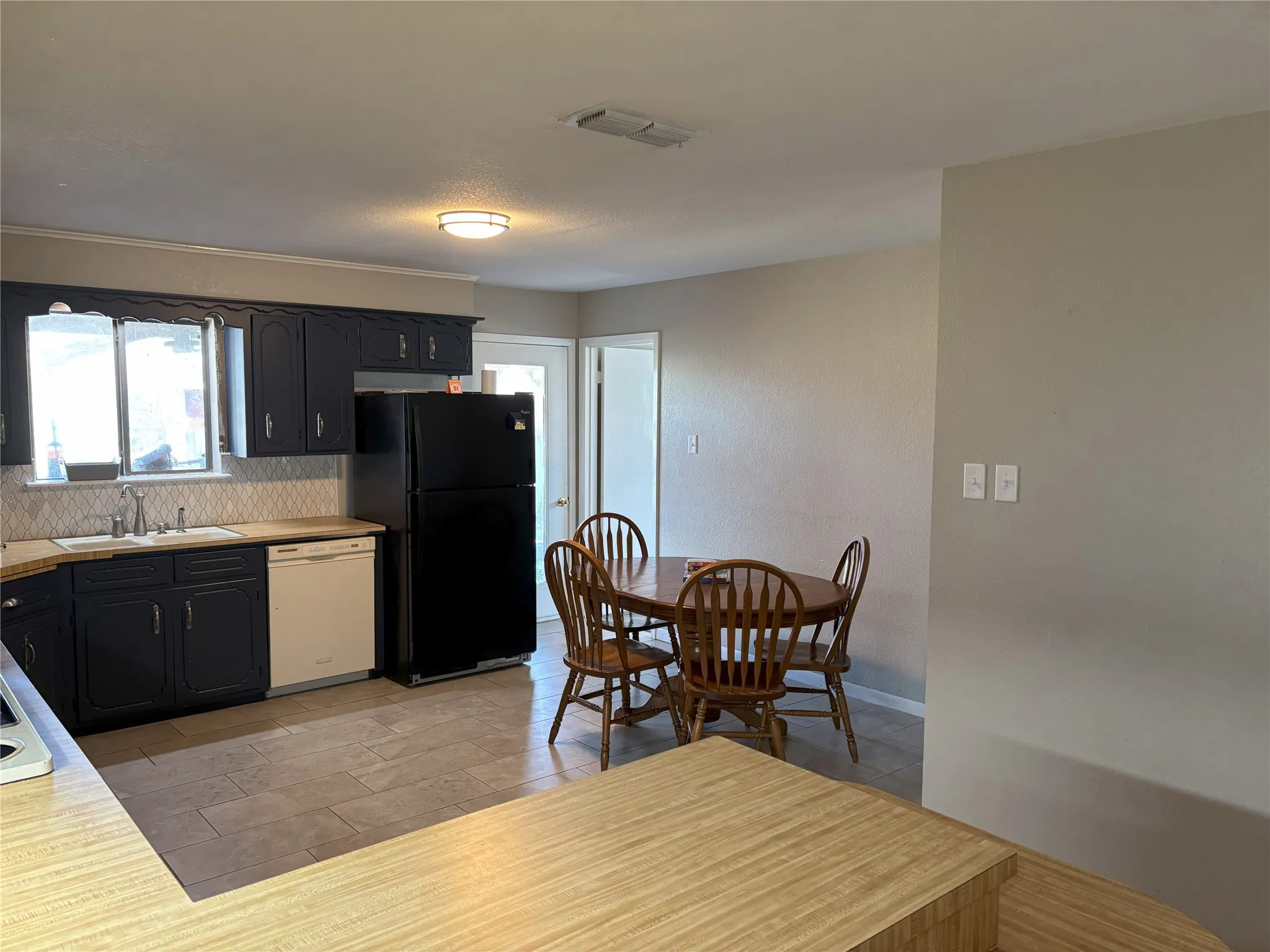 Kitchen featuring dishwasher, black refrigerator, sink, and tasteful backsplash