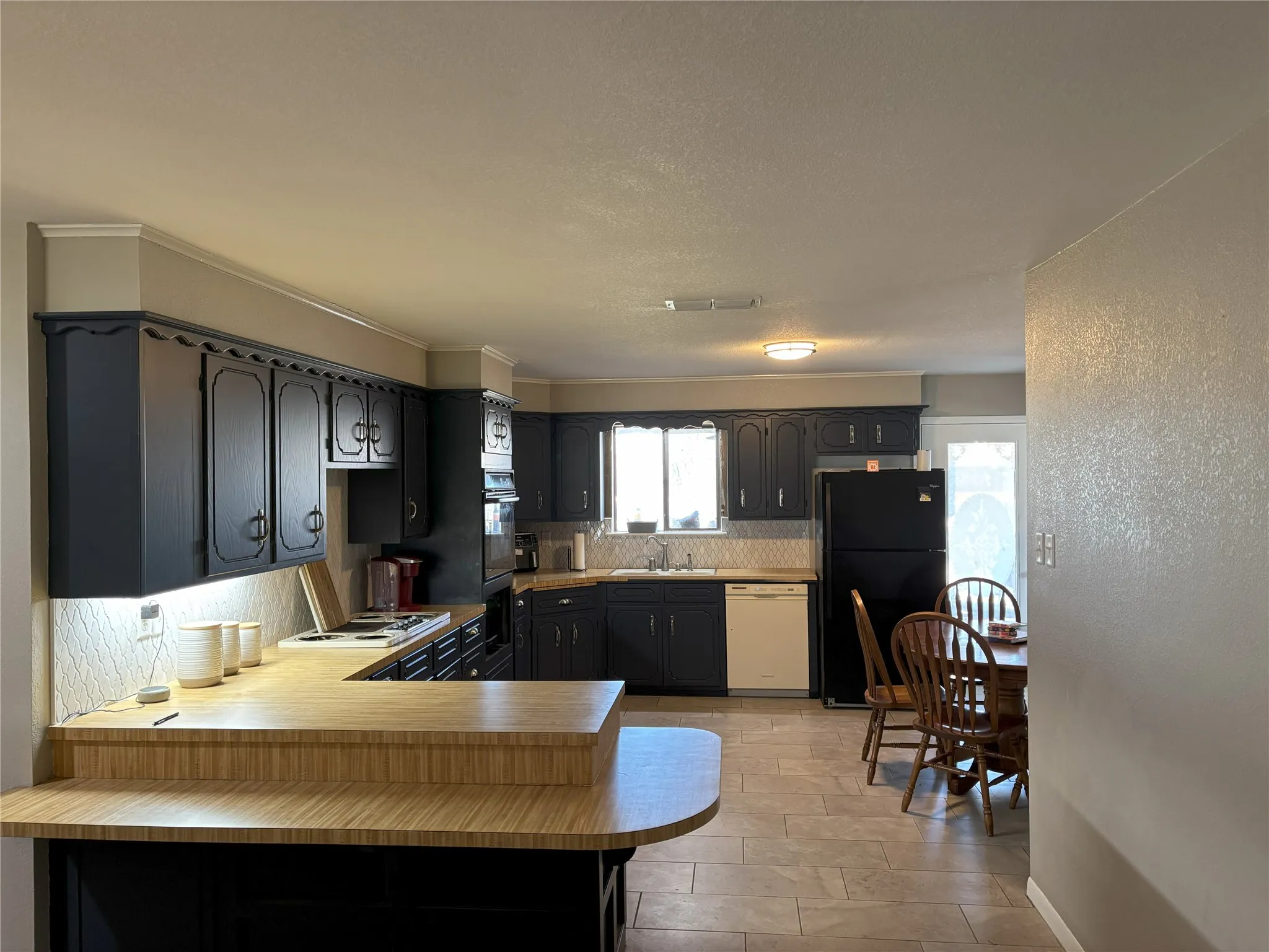 Kitchen with kitchen peninsula, decorative backsplash, white appliances, and sink