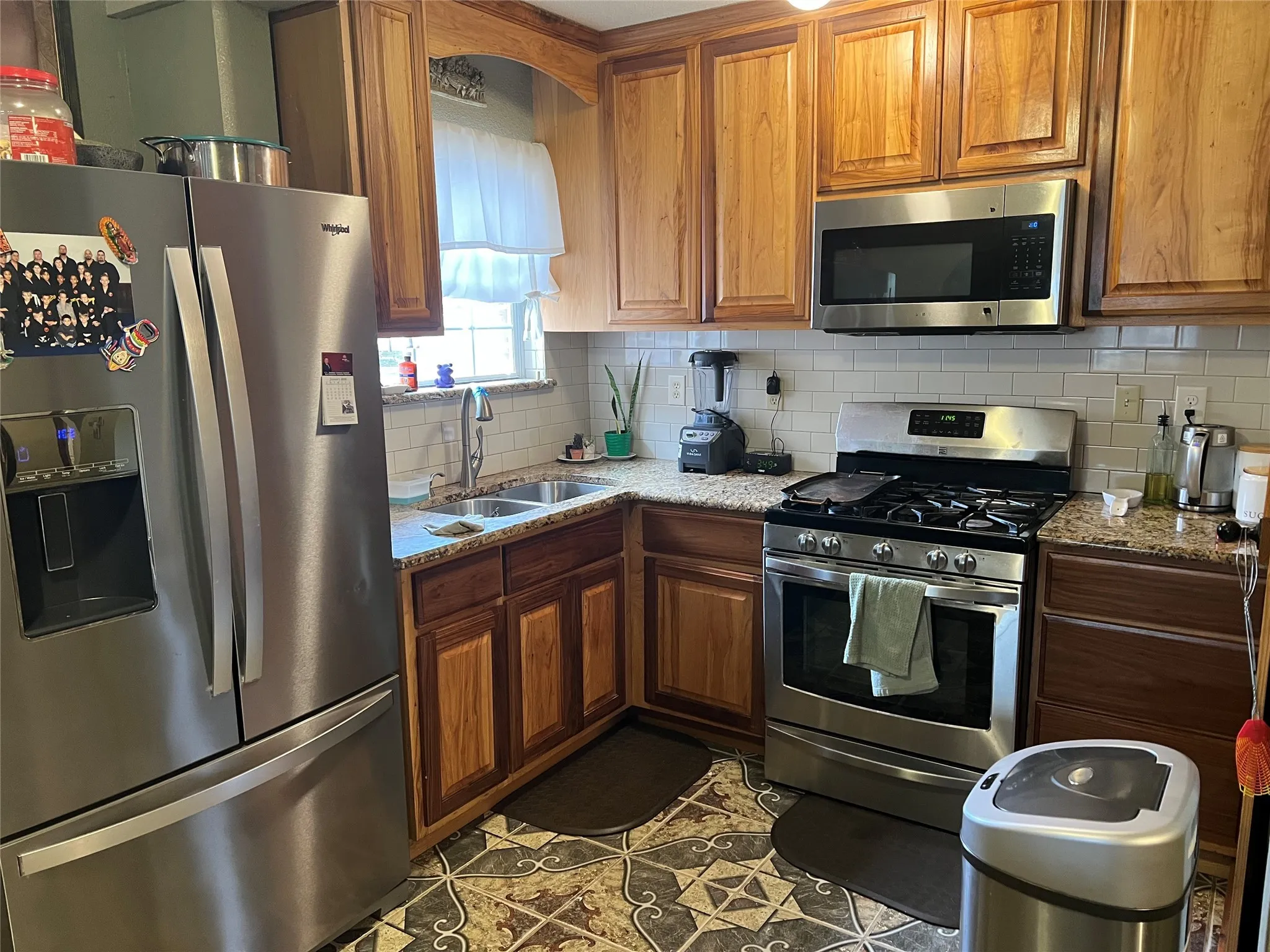 Kitchen featuring appliances with stainless steel finishes, sink, and light stone counters