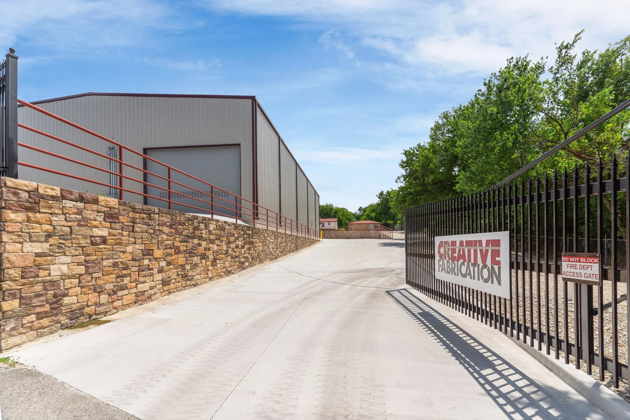 View from the street along with the electric gate and driveway with a curb