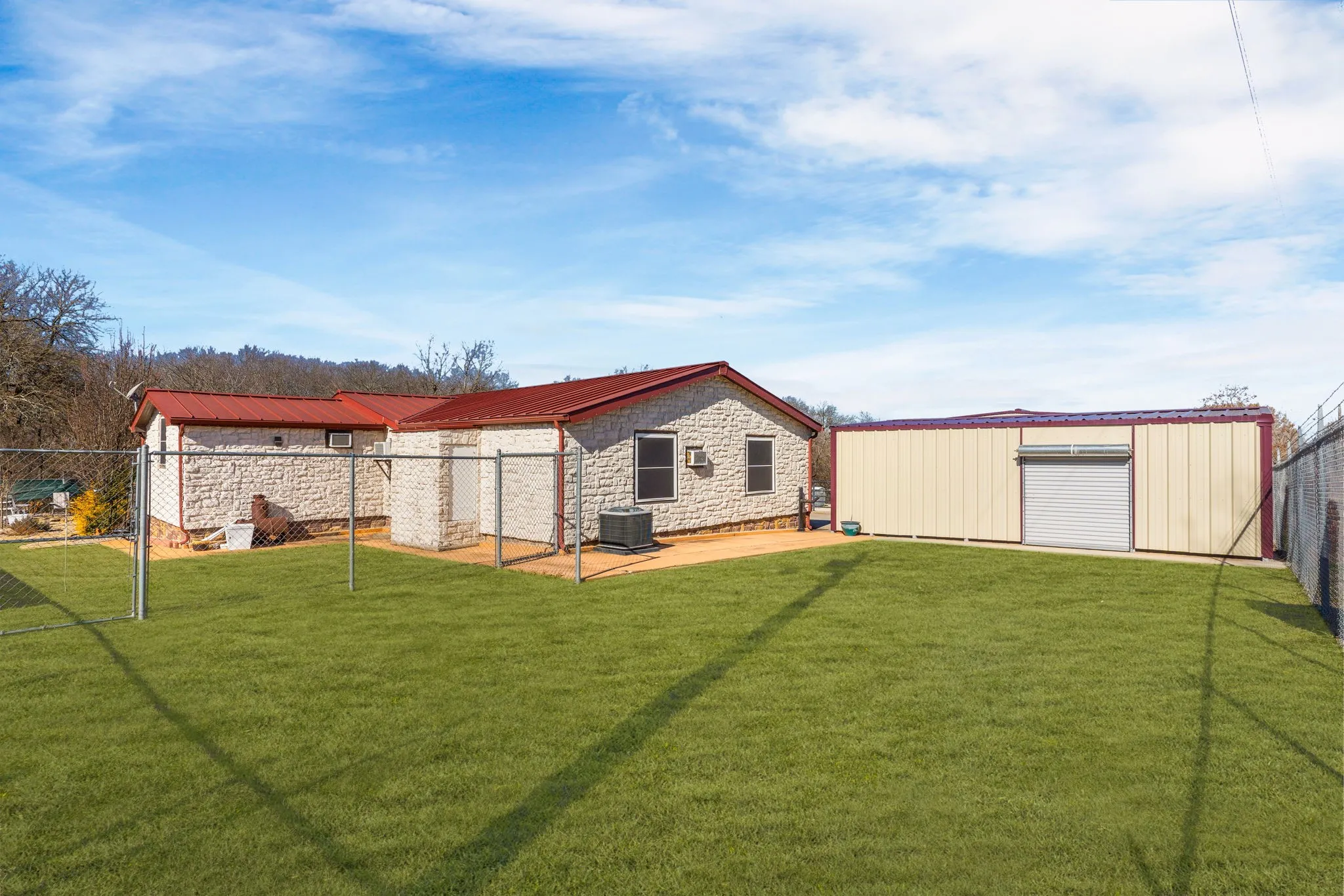 Rear view of property with a carport, back of home, central AC unit, and a lawn
