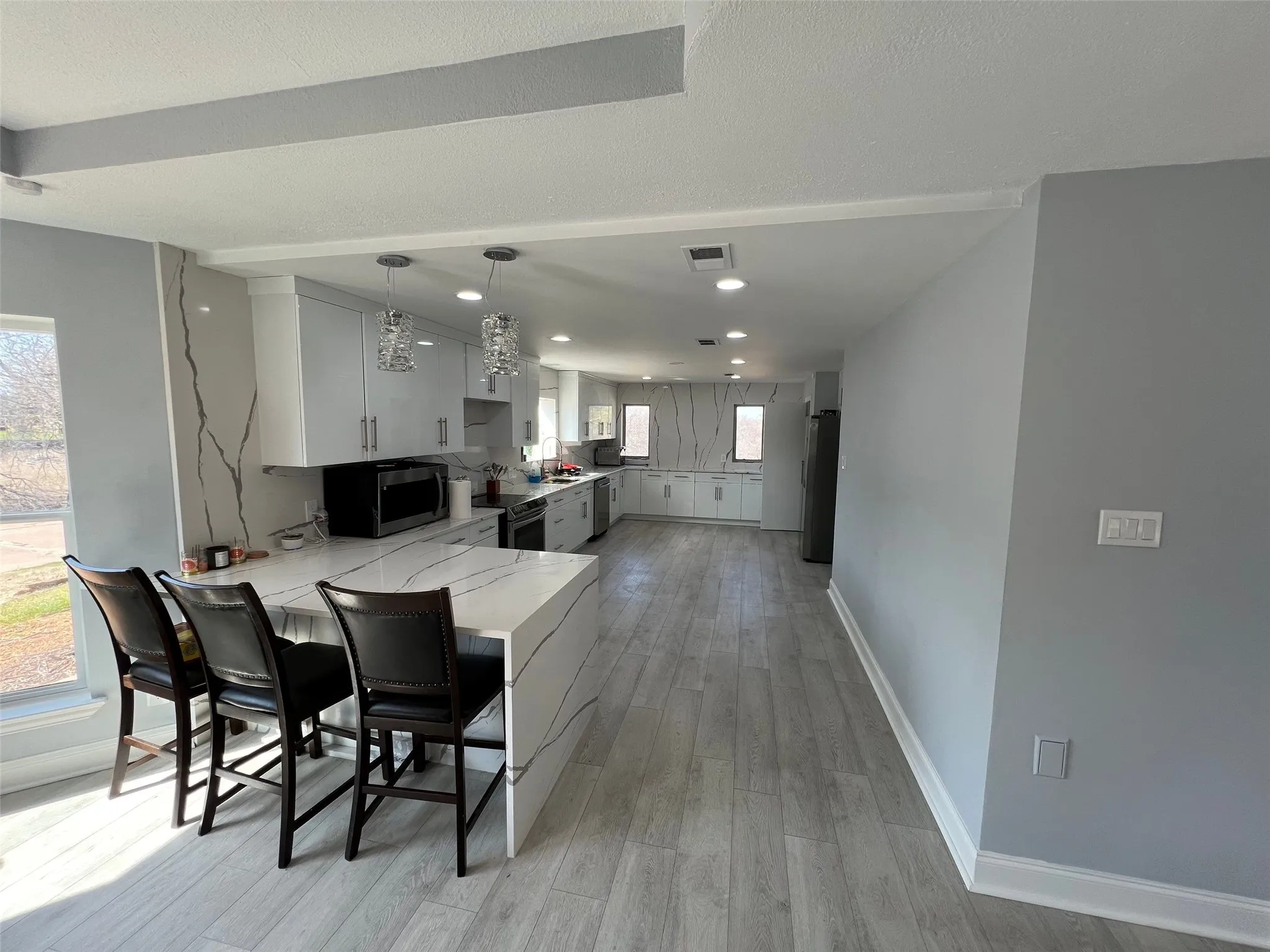Kitchen featuring gray cabinetry, a kitchen bar, light hardwood / wood-style floors, kitchen peninsula, and stainless steel appliances