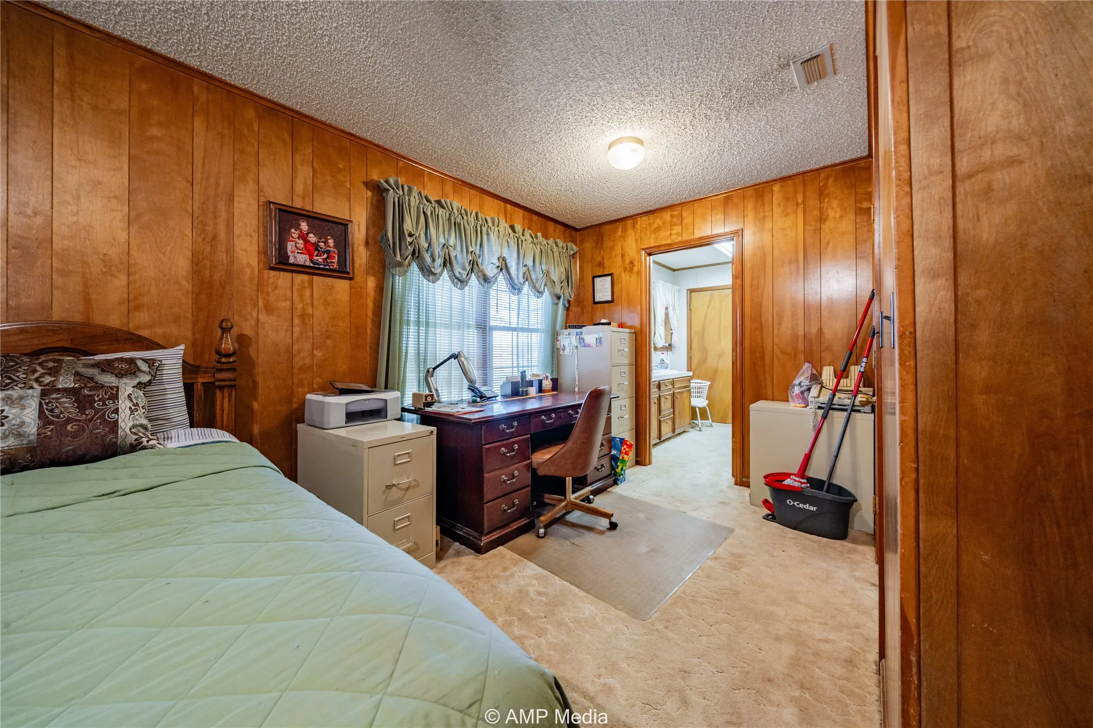 Carpeted bedroom featuring wooden walls and a textured ceiling
