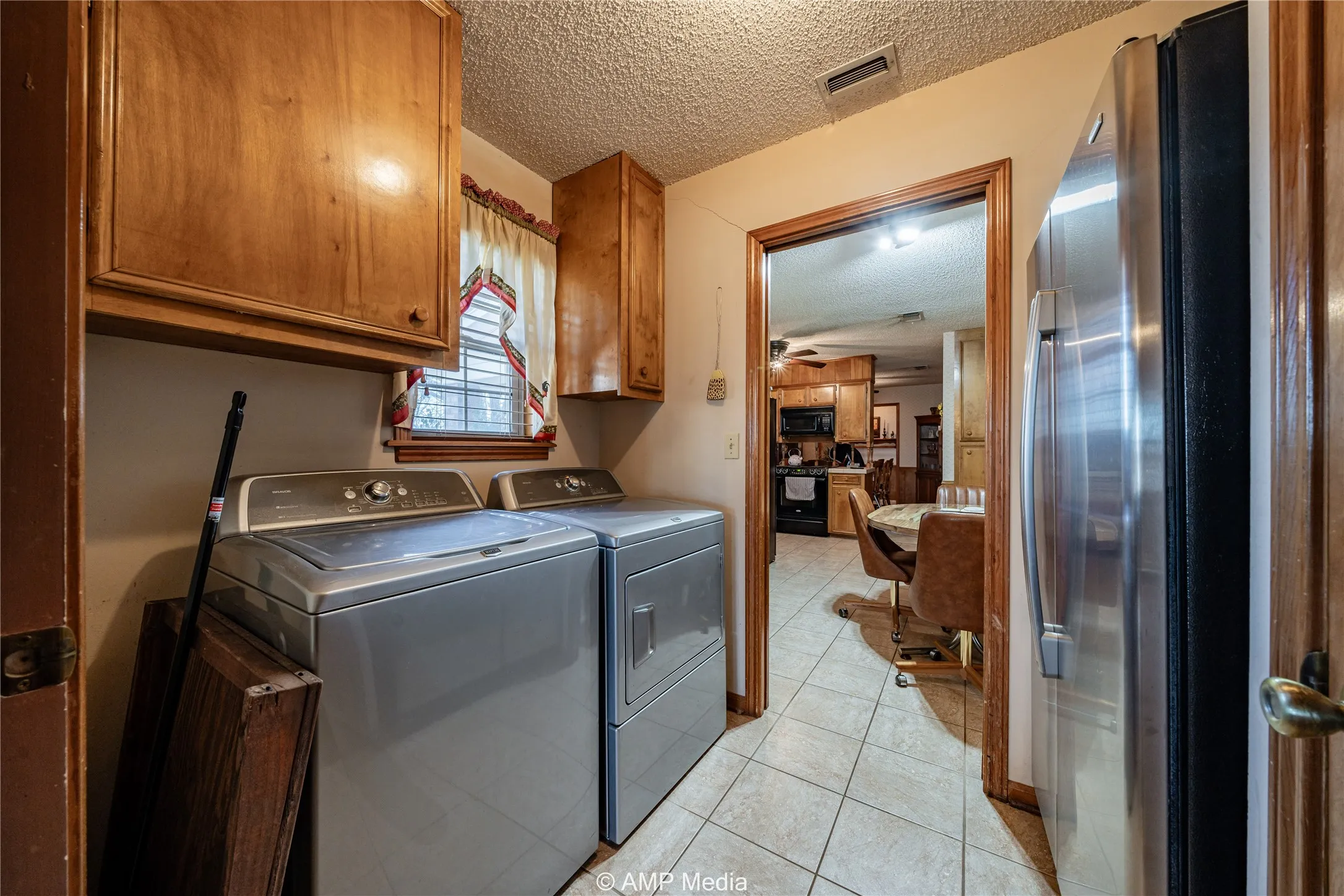 Clothes washing area featuring cabinets, a textured ceiling, light tile patterned floors, ceiling fan, and washing machine and dryer