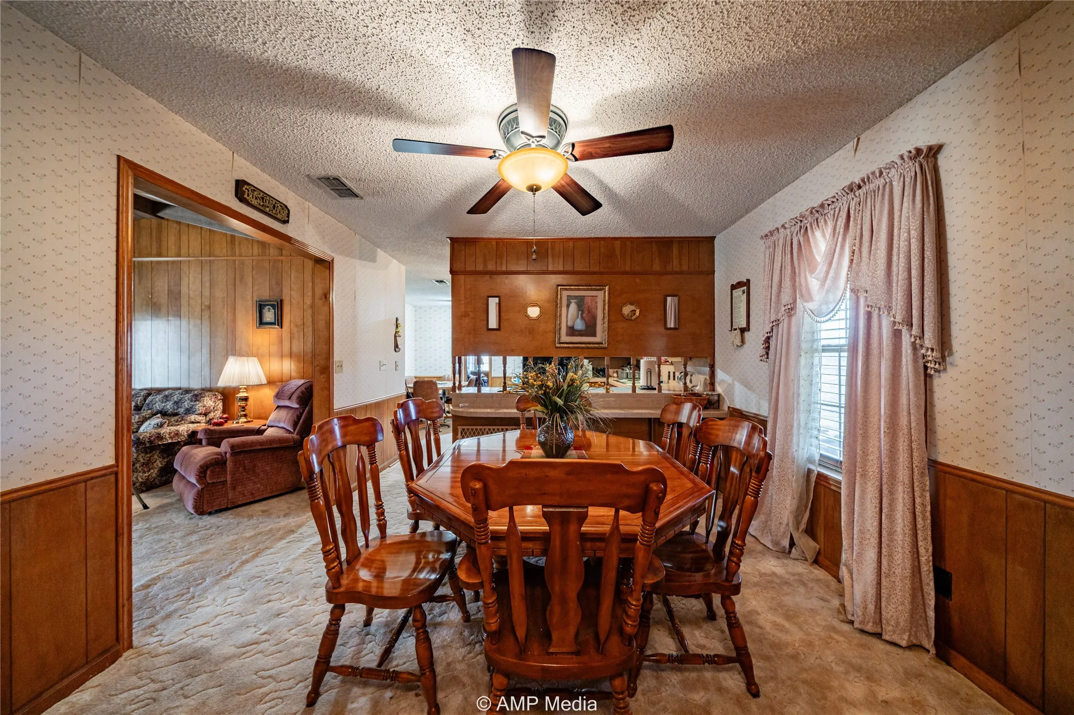 Dining area with ceiling fan, light colored carpet, and a textured ceiling