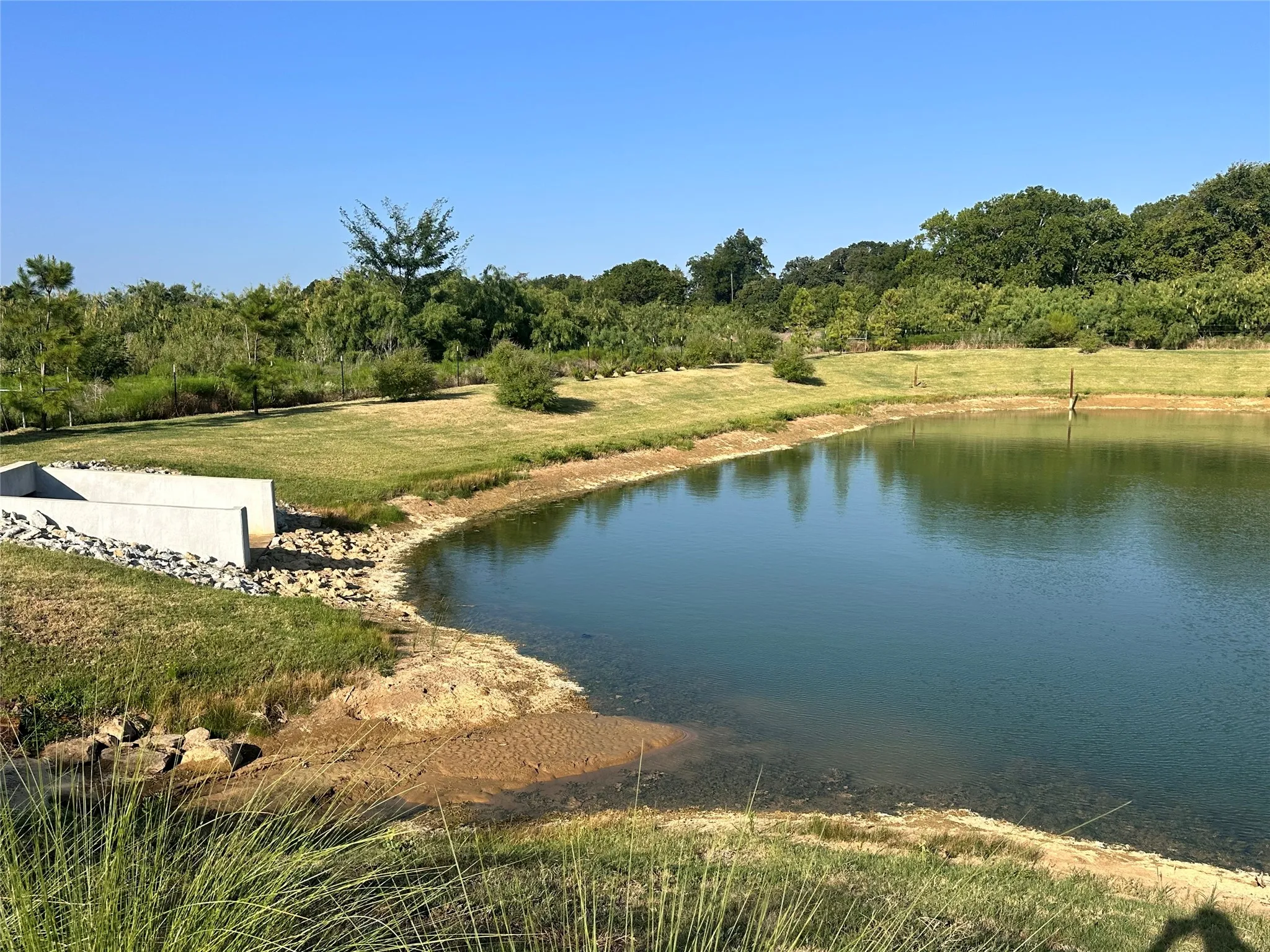 Expansive pond with surrounding grassy areas and mature trees