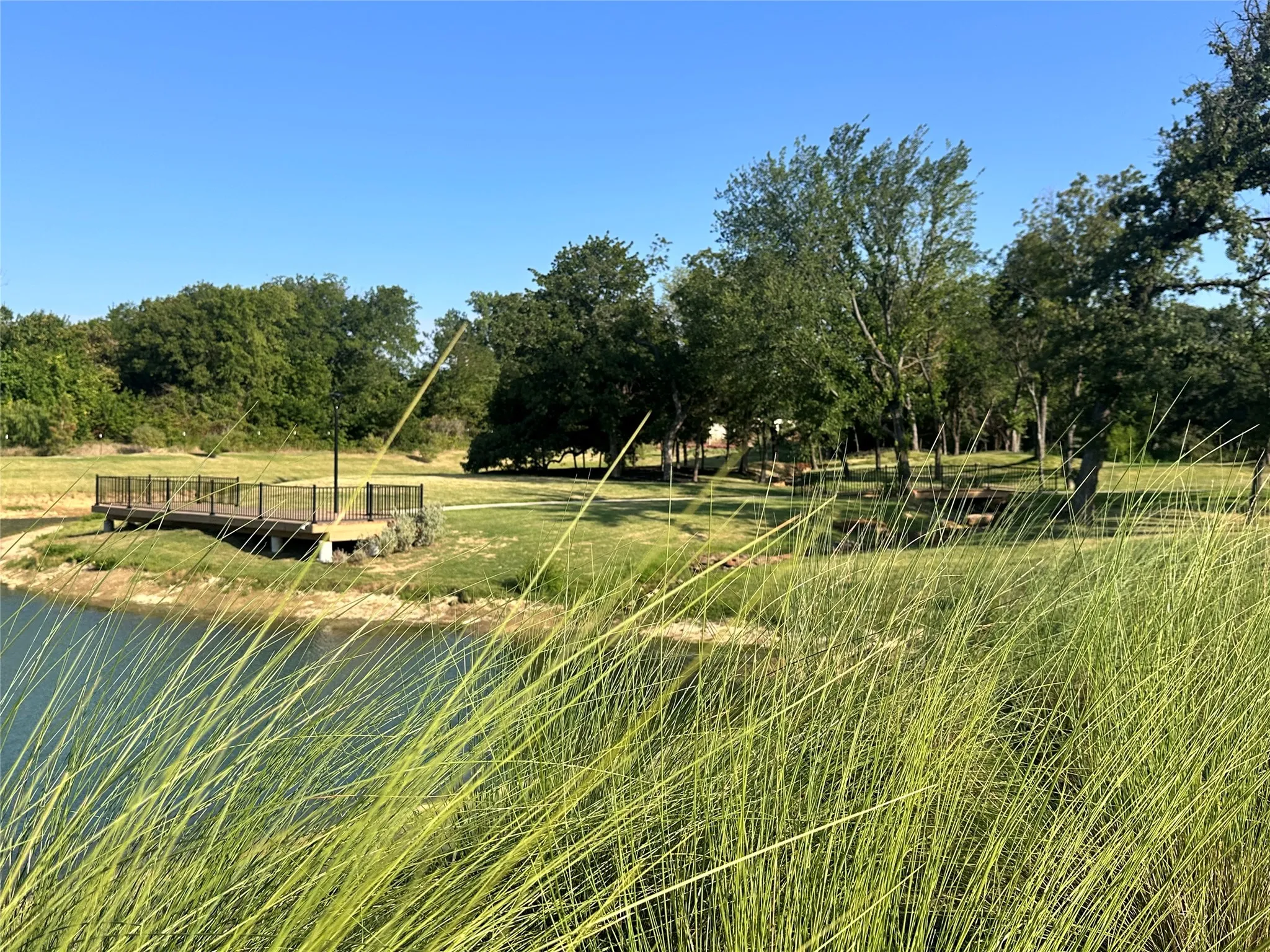 Expansive pond with surrounding grassy areas and mature trees