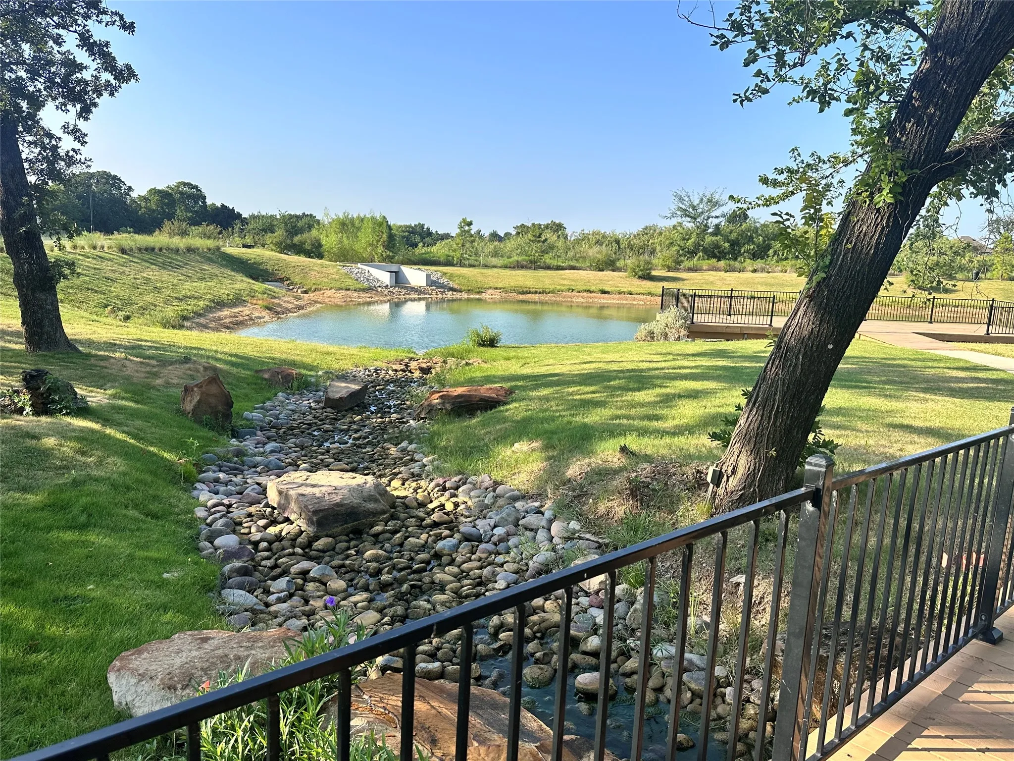 Waterside deck with black metal railing and natural landscaping