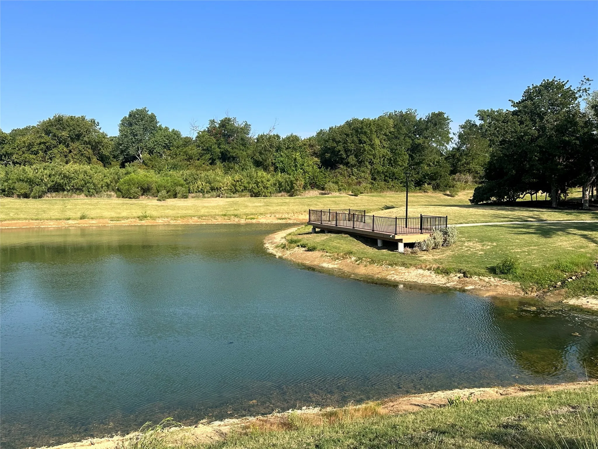Expansive pond with a built-in wooden deck and metal railing