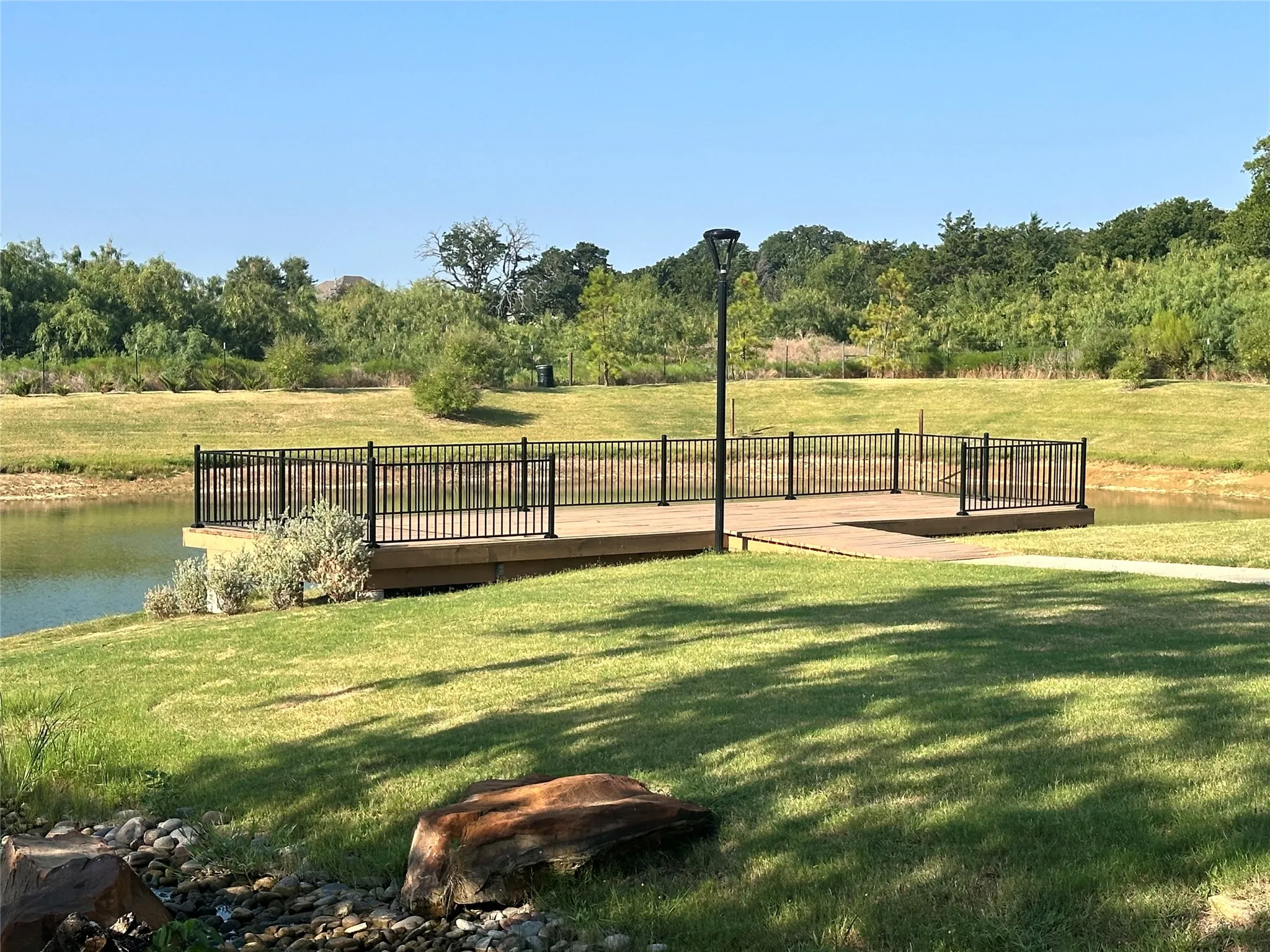 Waterside deck with black metal railing and natural landscaping