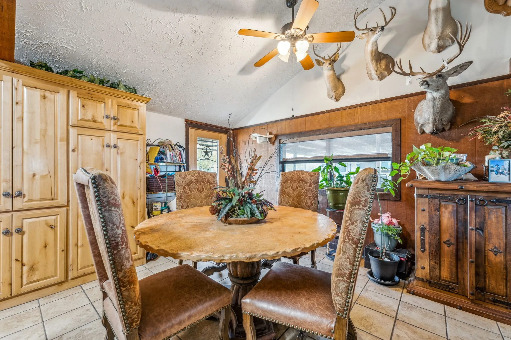 Dining area with lofted ceiling, light tile patterned floors, ceiling fan, and a textured ceiling