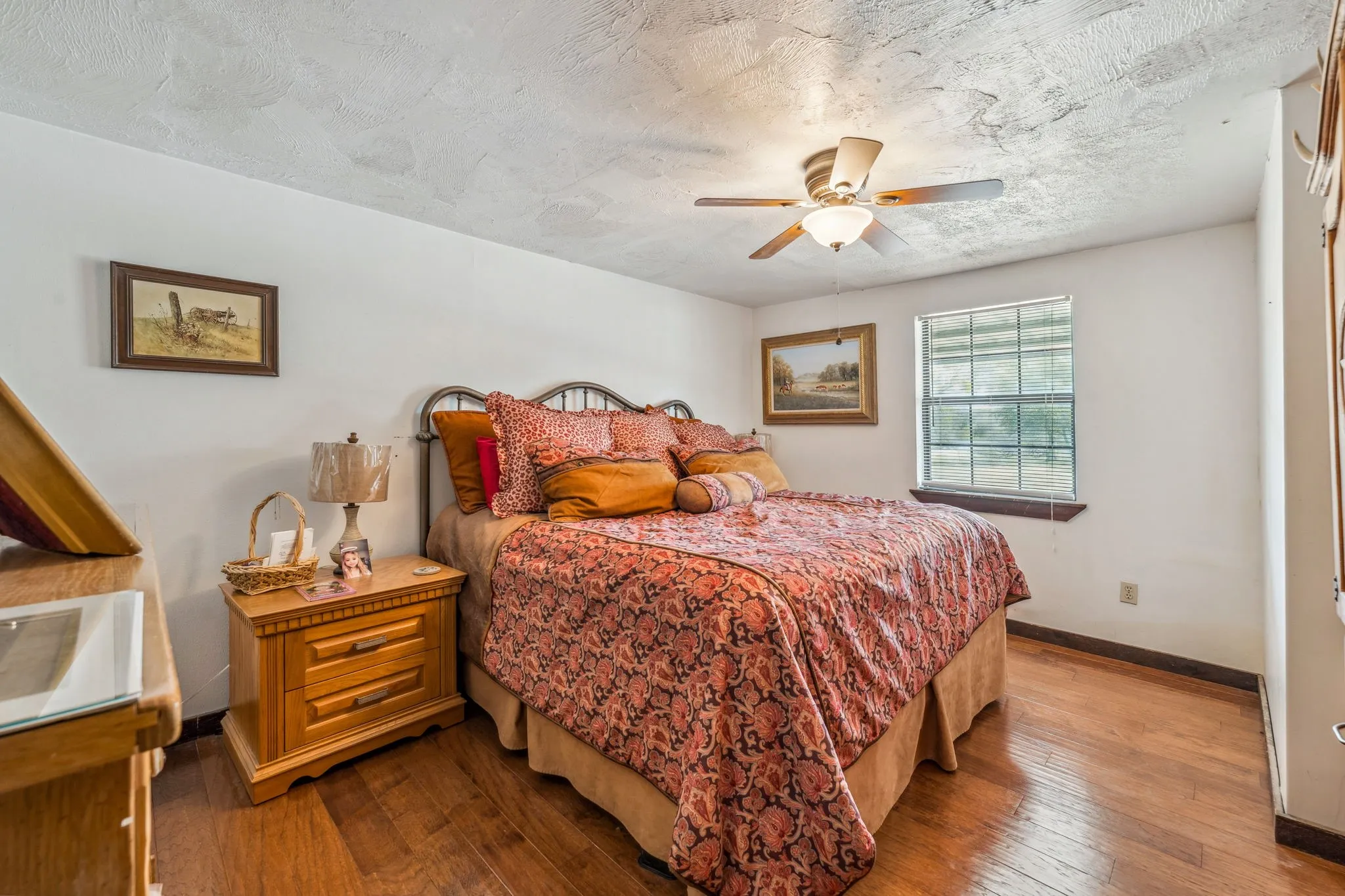 Bedroom featuring a ceiling fan, a textured ceiling, baseboards, and hardwood / wood-style flooring