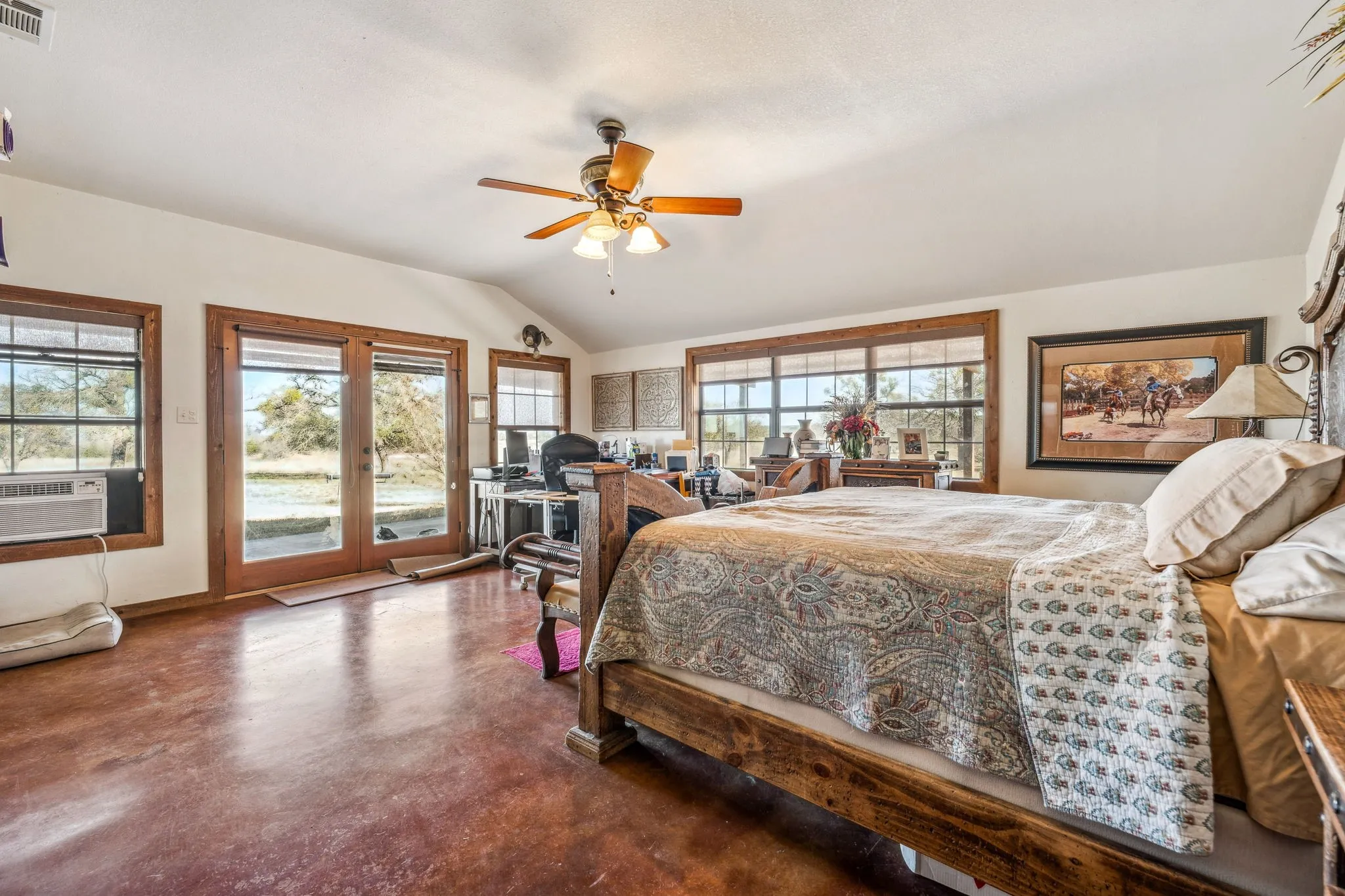 Bedroom featuring finished concrete flooring, visible vents, access to outside, vaulted ceiling, and cooling unit