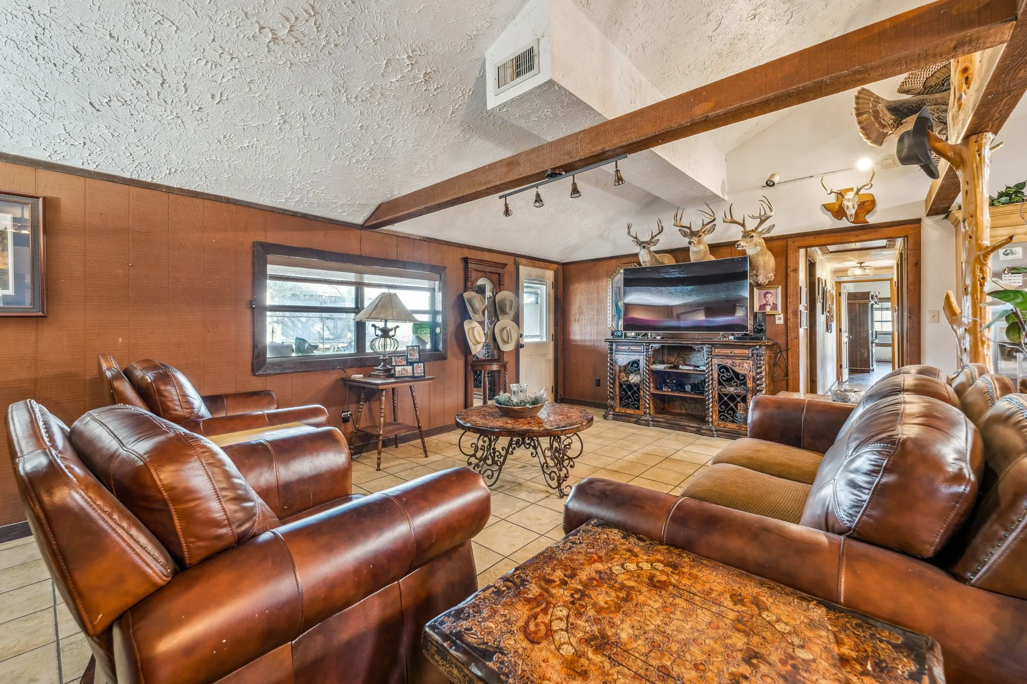 Living area with vaulted ceiling with beams, visible vents, wooden walls, a textured ceiling, and tile patterned floors