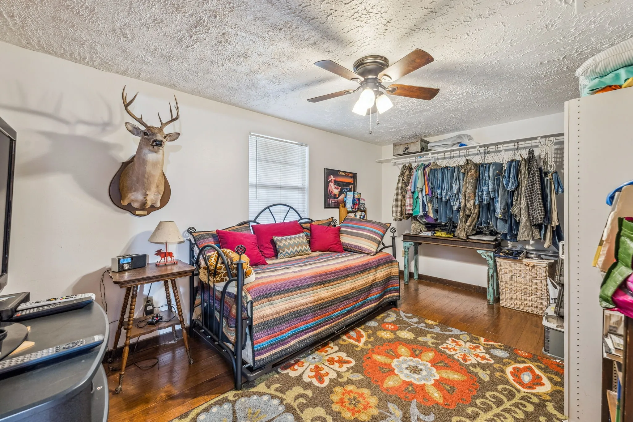 Bedroom with a closet, wood-type flooring, a ceiling fan, a textured ceiling, and baseboards