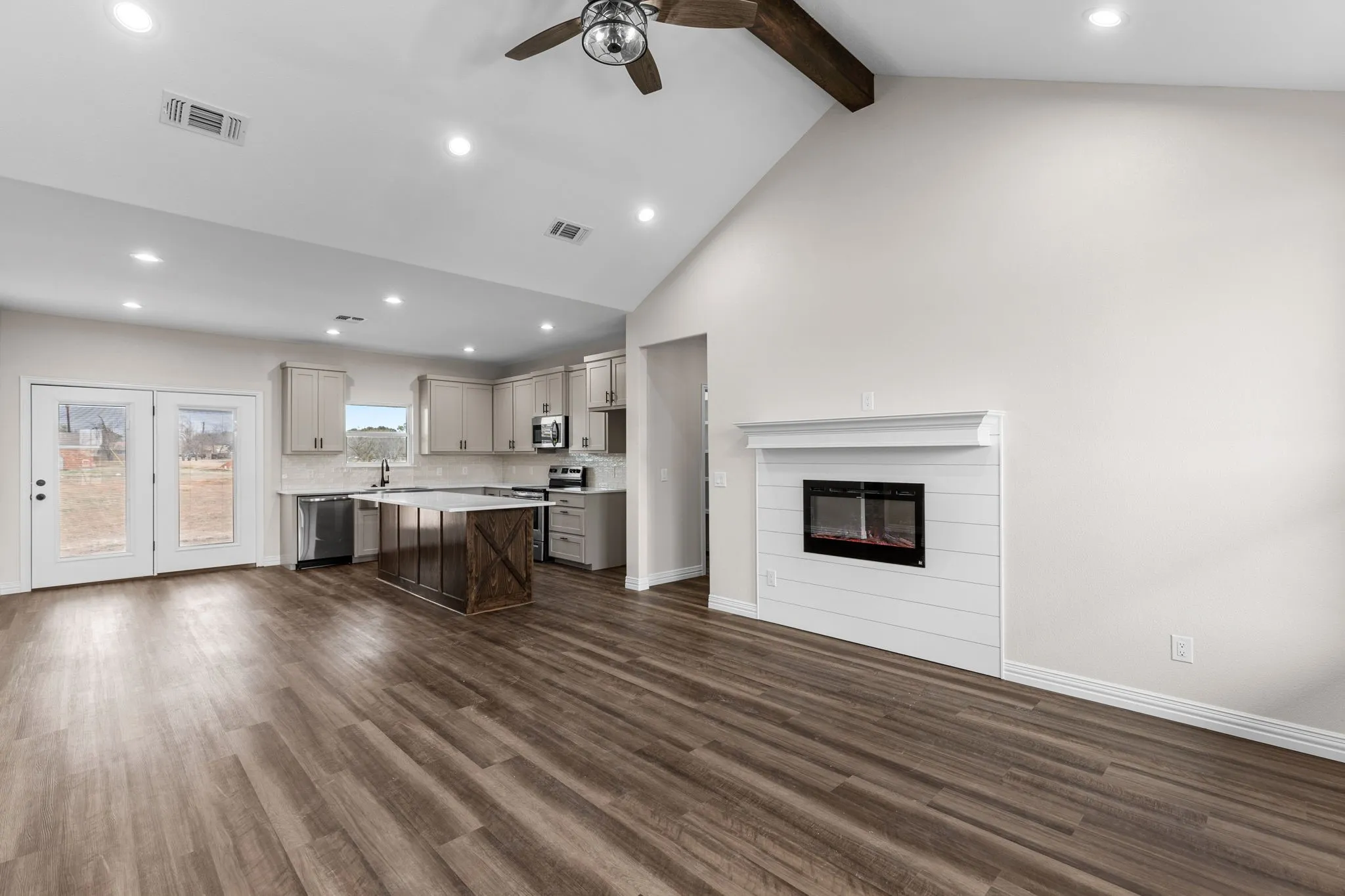 Kitchen with gray cabinetry, a kitchen breakfast bar, a kitchen island, stainless steel appliances, and beam ceiling