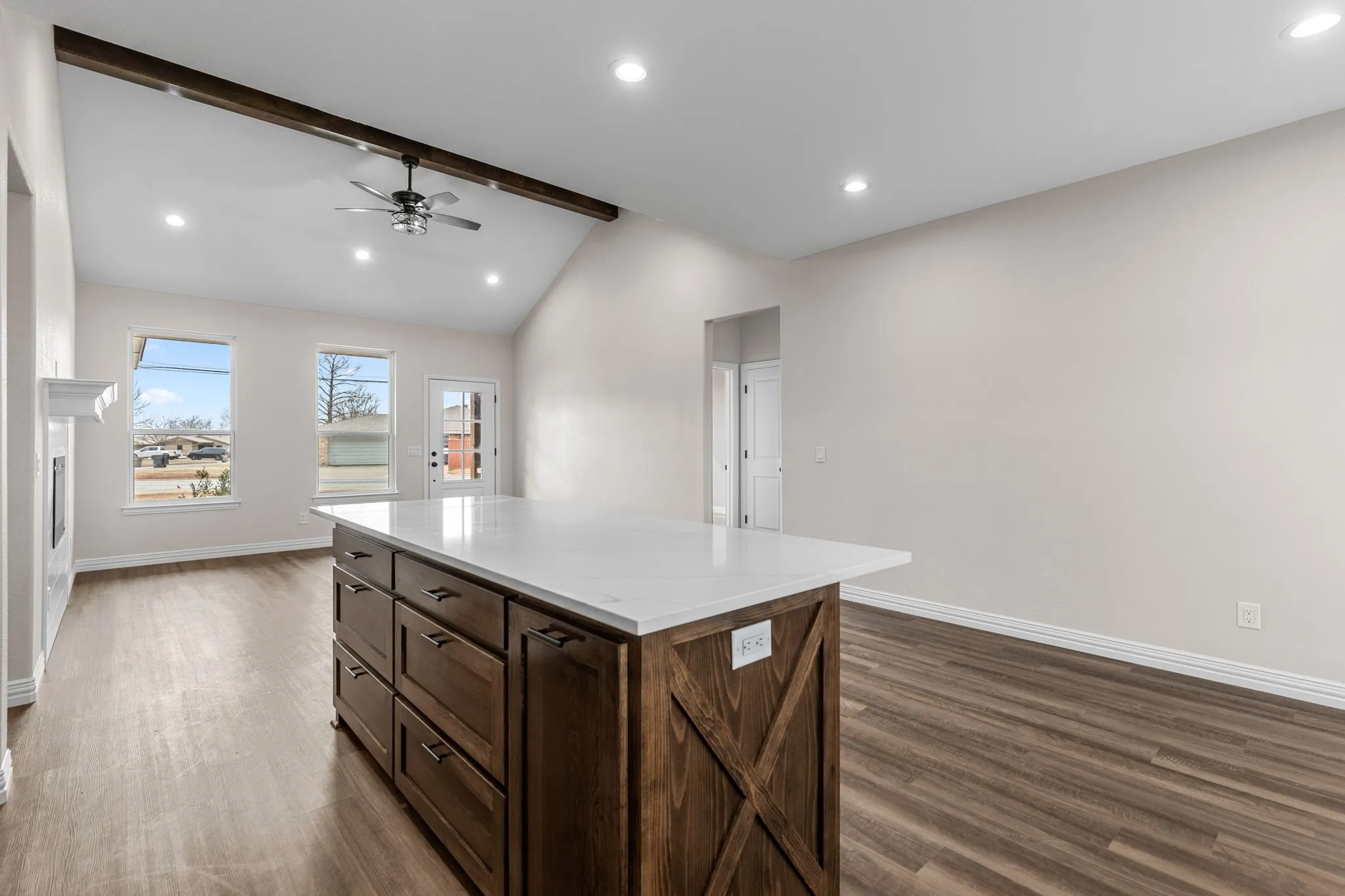 Kitchen featuring dark wood-type flooring, ceiling fan, a kitchen island, and vaulted ceiling with beams