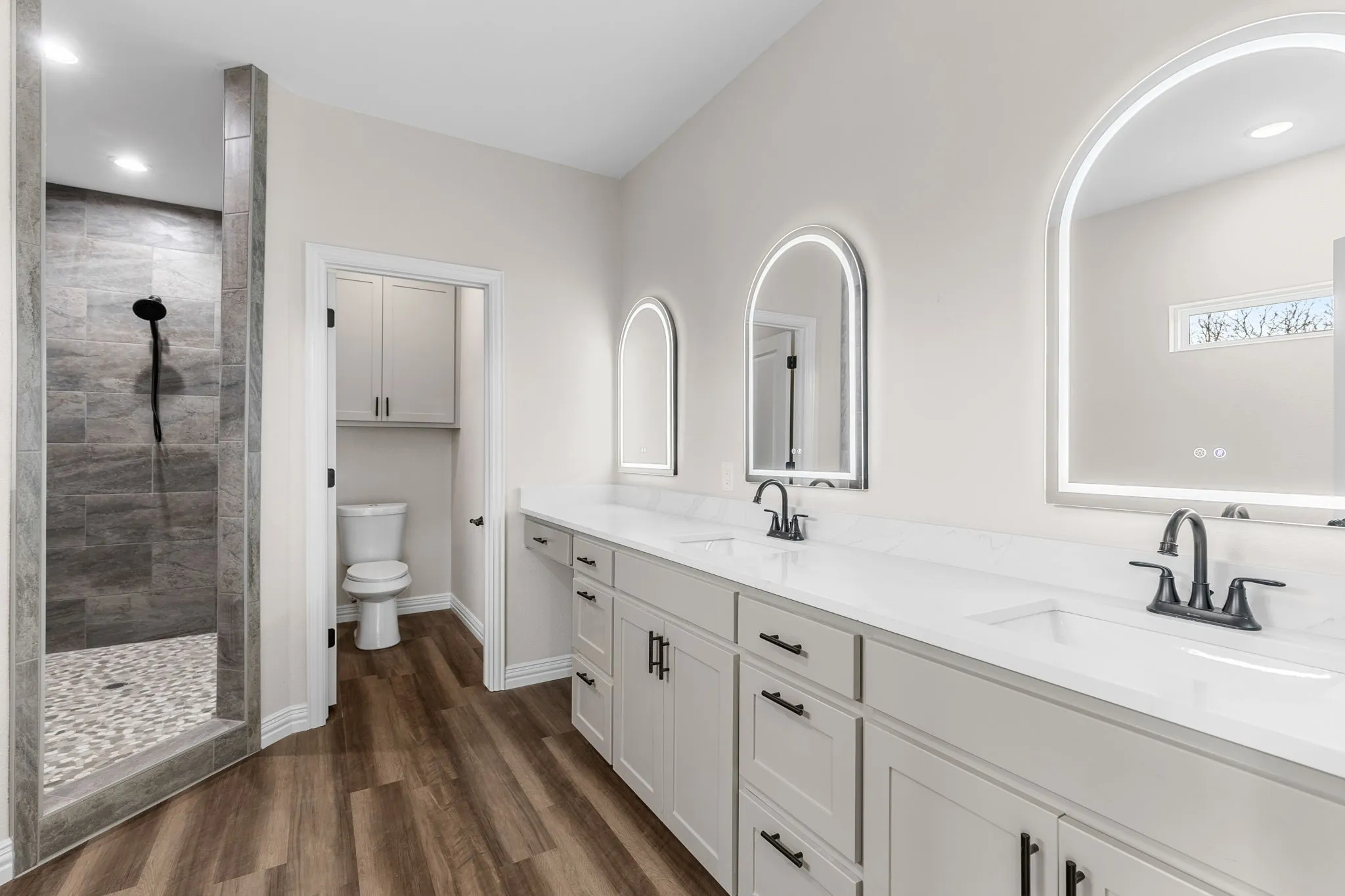 Bathroom featuring wood-type flooring, toilet, vanity, and a tile shower