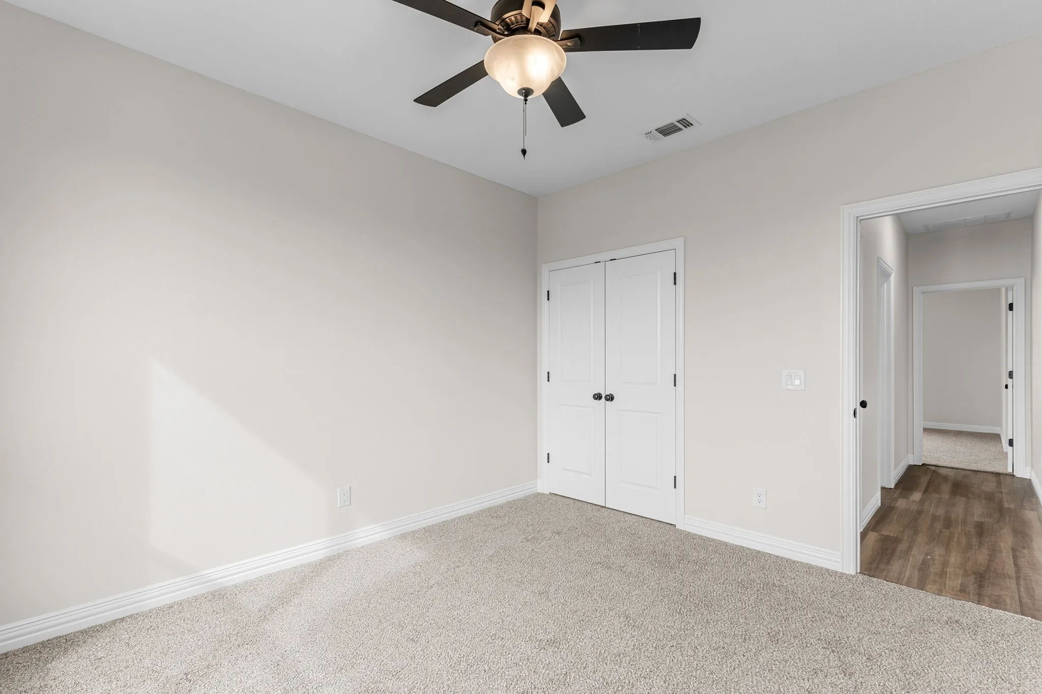 Unfurnished bedroom featuring dark carpet, a closet, and ceiling fan