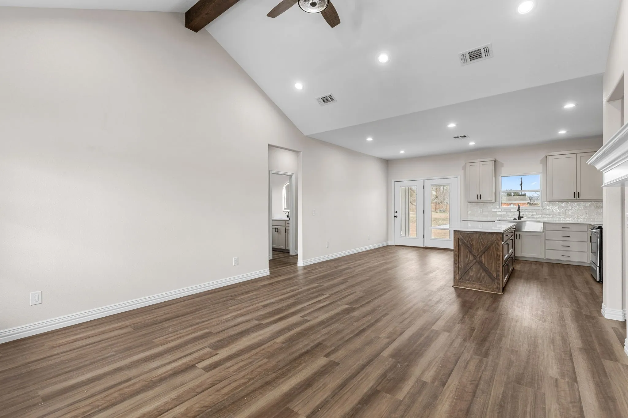 Unfurnished living room with dark wood-type flooring, sink, high vaulted ceiling, beamed ceiling, and ceiling fan