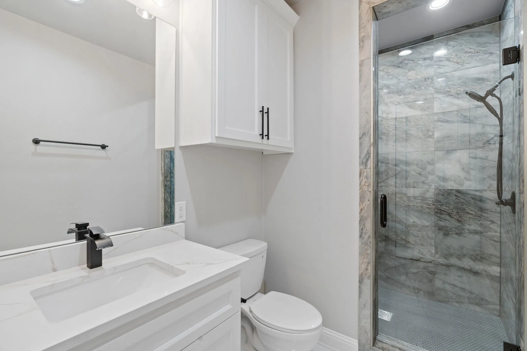 Bathroom featuring a shower with door, vanity, and toilet
