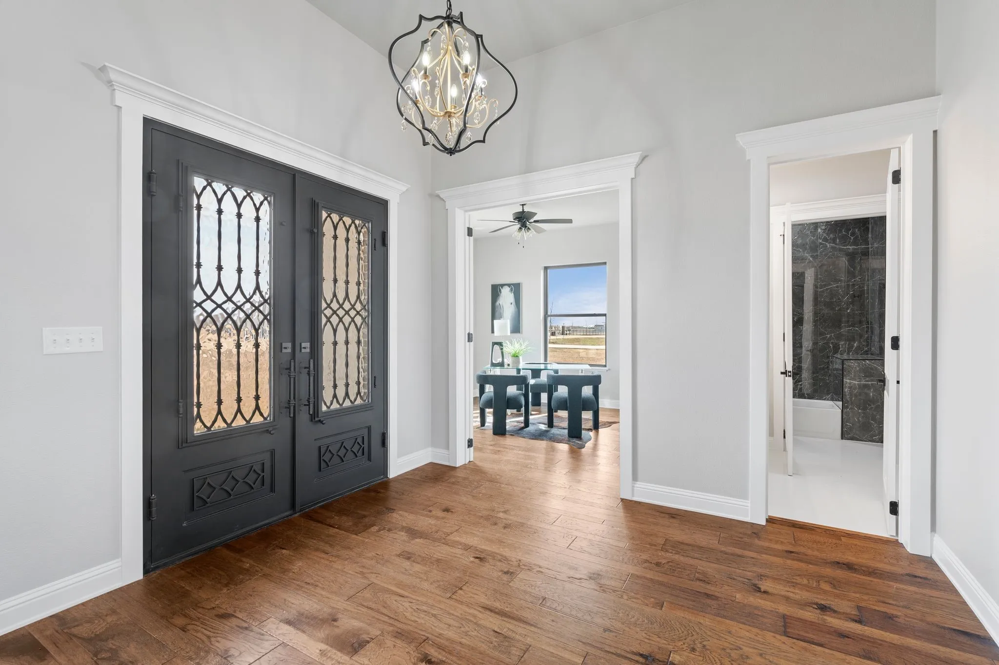 Foyer entrance with ceiling fan with notable chandelier, french doors, and hardwood / wood-style flooring
