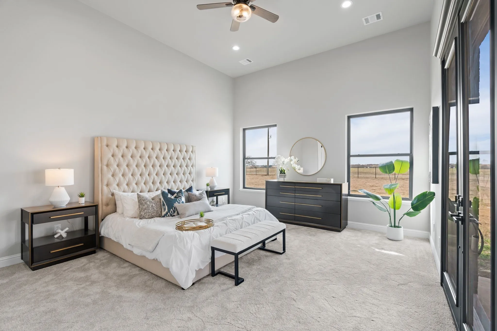 Carpeted bedroom with ceiling fan and high vaulted ceiling