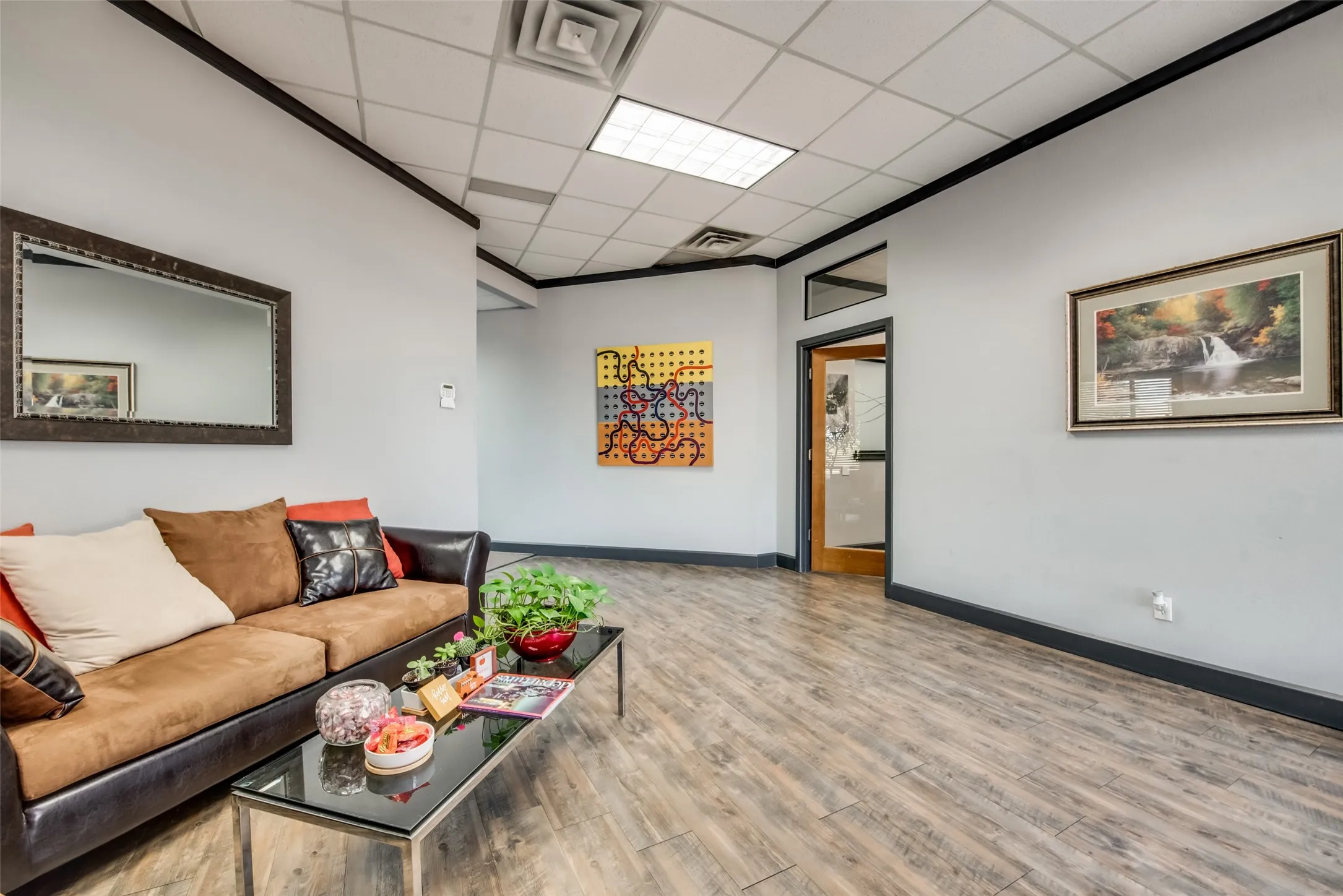 Living room featuring ornamental molding, wood-type flooring, and a drop ceiling