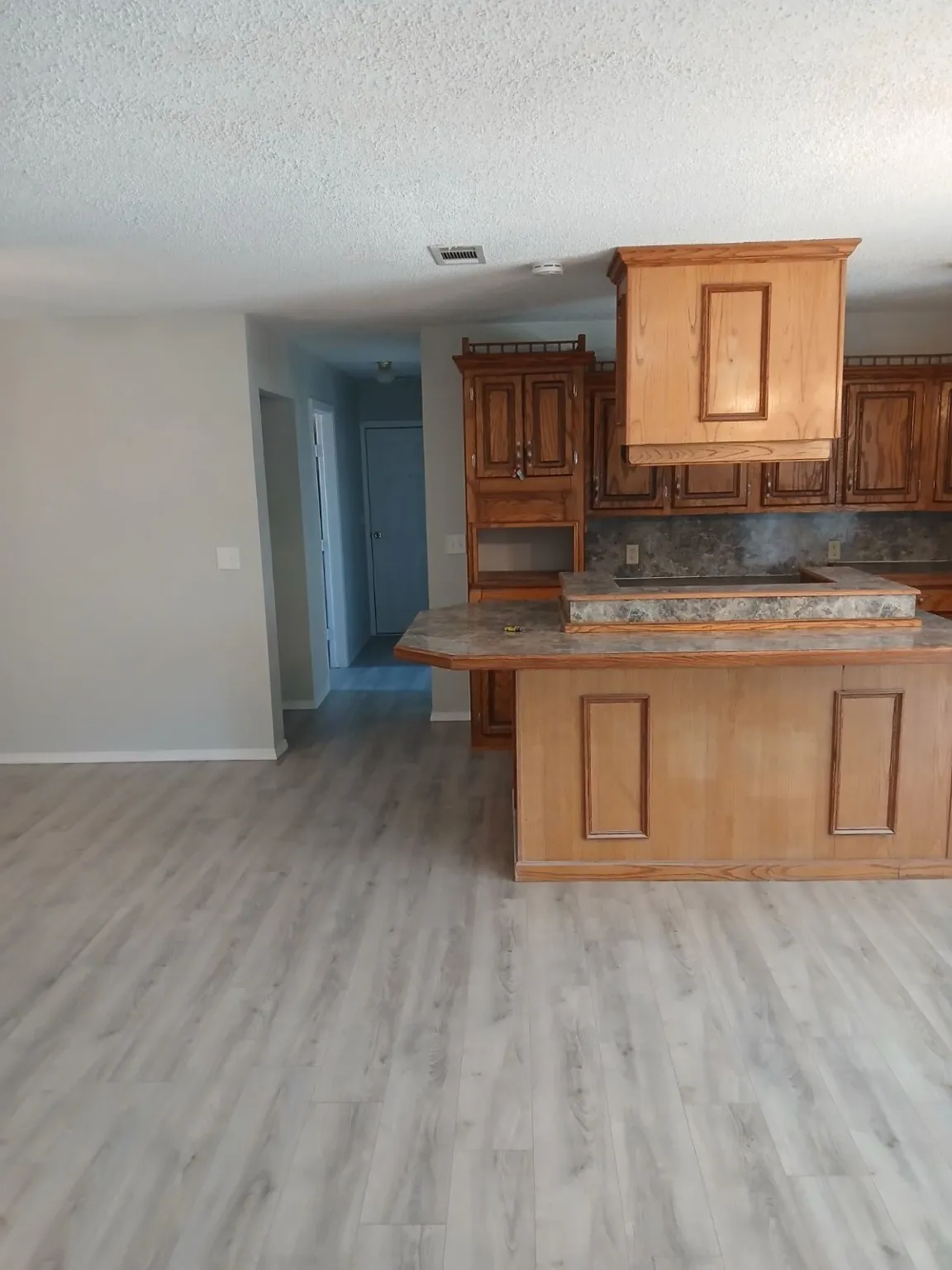 Kitchen with tasteful backsplash, a kitchen bar, a textured ceiling, and light wood-type flooring