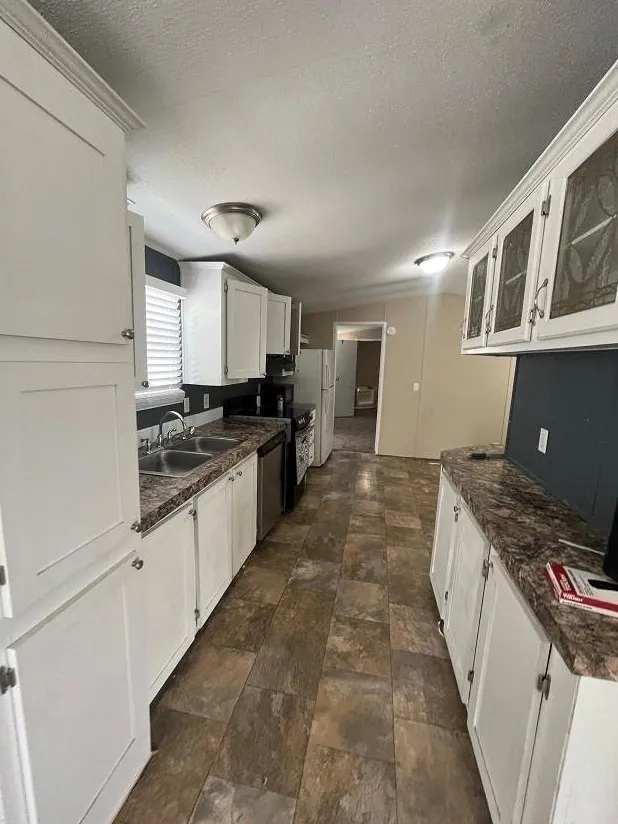 Kitchen featuring white cabinets, dark tile patterned floors, stove, and sink