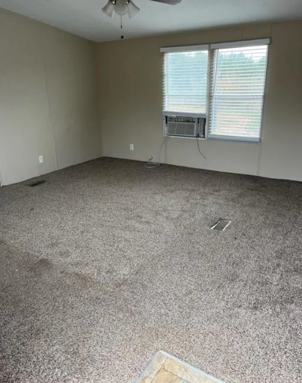 Carpeted spare room with ceiling fan and cooling unit