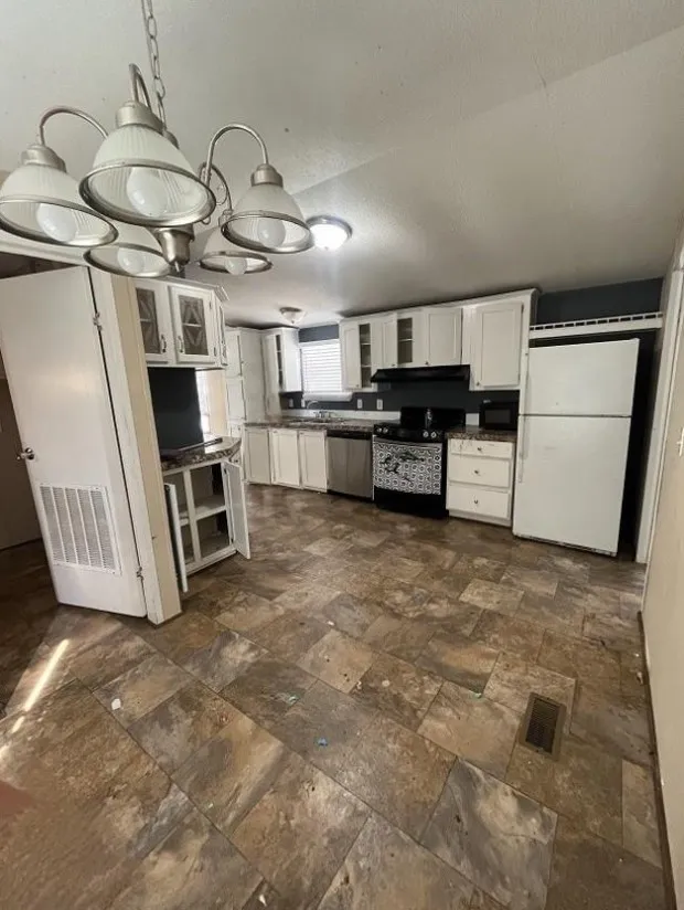 Kitchen featuring stainless steel dishwasher, white cabinetry, white refrigerator, range with electric cooktop, and dark tile patterned flooring
