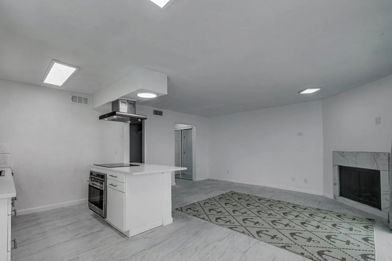 Kitchen with range hood, white cabinetry, oven, a premium fireplace, and black electric cooktop