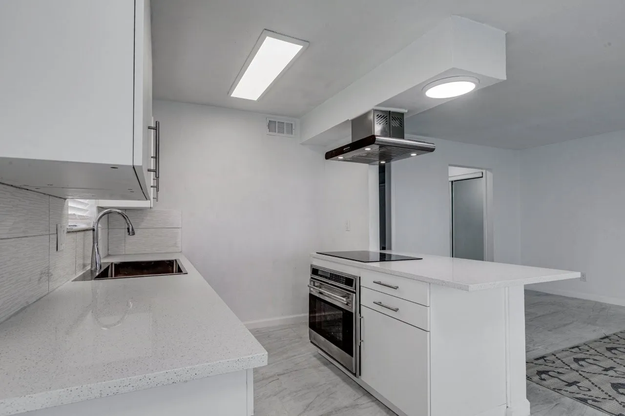 Kitchen with sink, white cabinetry, stainless steel oven, island range hood, and black electric cooktop