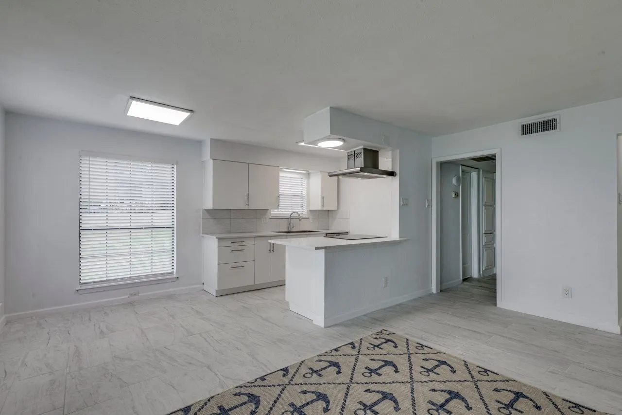 Kitchen with sink, tasteful backsplash, black electric stovetop, white cabinets, and kitchen peninsula