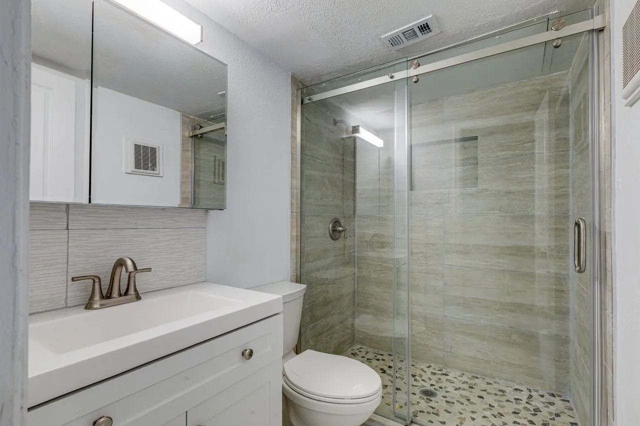 Bathroom with vanity, tasteful backsplash, toilet, and walk in shower