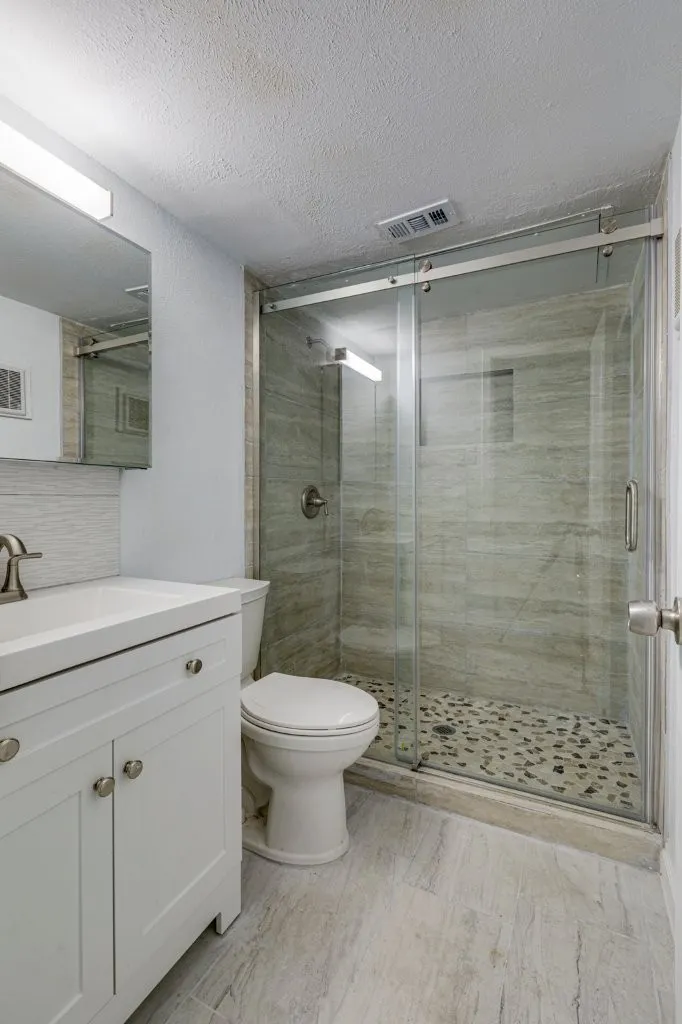 Bathroom featuring decorative backsplash, vanity, toilet, a shower with door, and a textured ceiling
