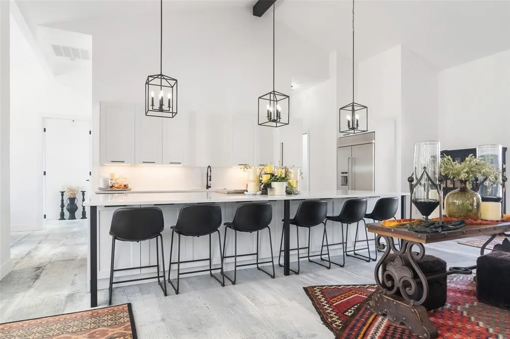 Kitchen with built in refrigerator, white cabinetry, hanging light fixtures, and a breakfast bar area