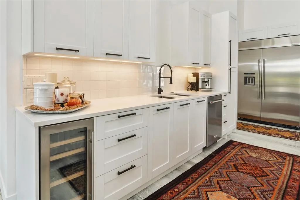 Kitchen featuring sink, stainless steel built in fridge, beverage cooler, decorative backsplash, and white cabinets