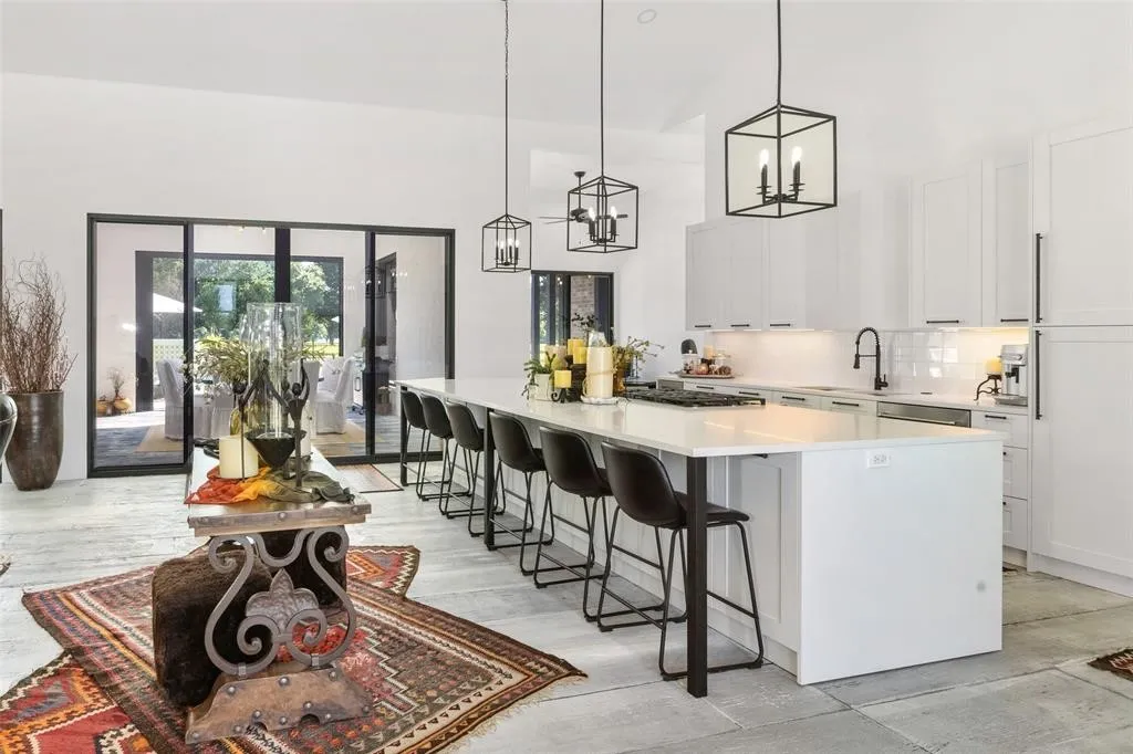 Bar featuring sink, tasteful backsplash, stainless steel gas cooktop, white cabinets, and decorative light fixtures