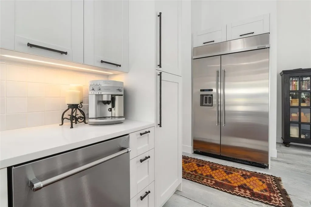 Kitchen featuring decorative backsplash, stainless steel appliances, and white cabinets
